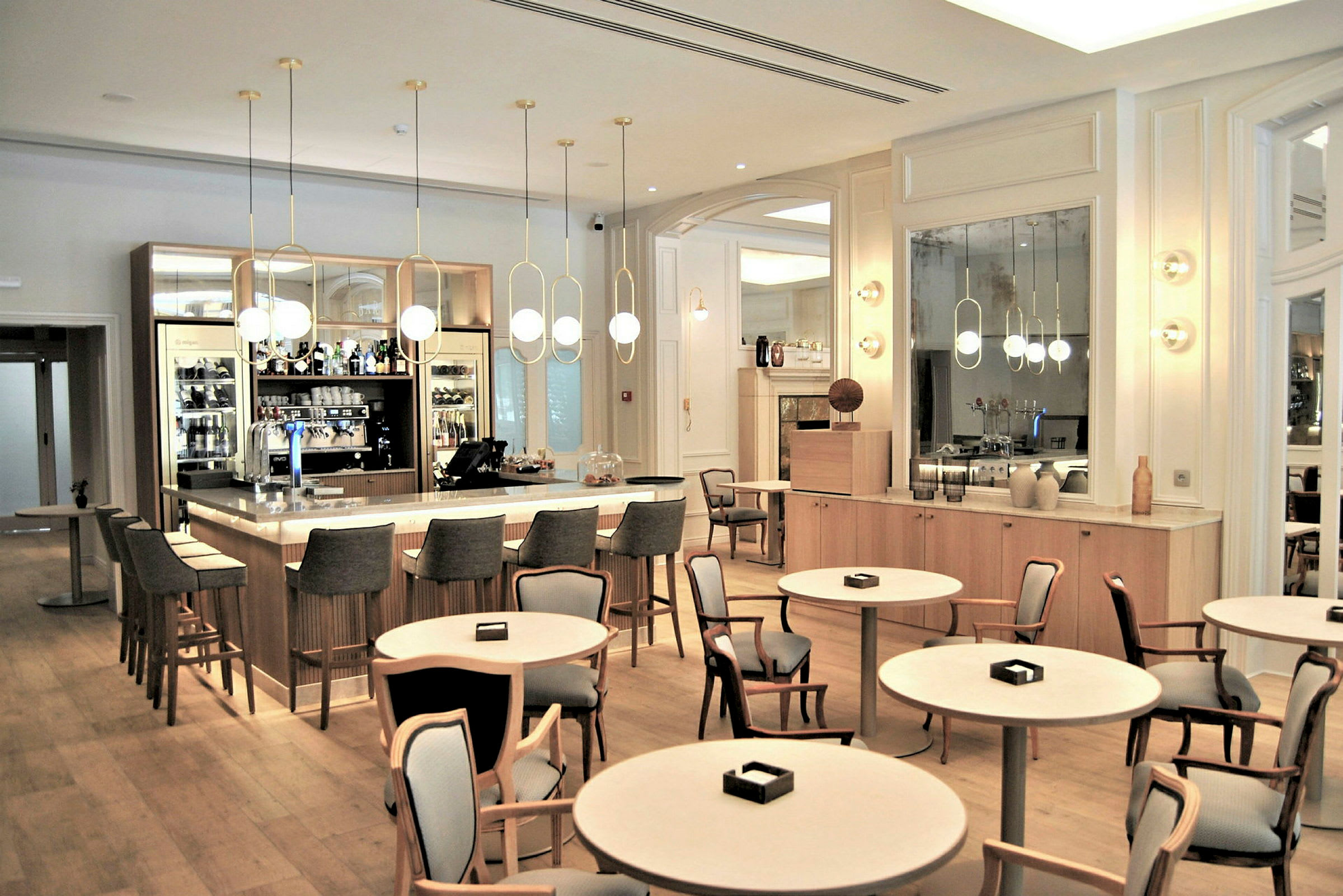 En elegant bar med et stort rundt bord og stole i en lys, moderne indretning. (AI-genereret tekst)