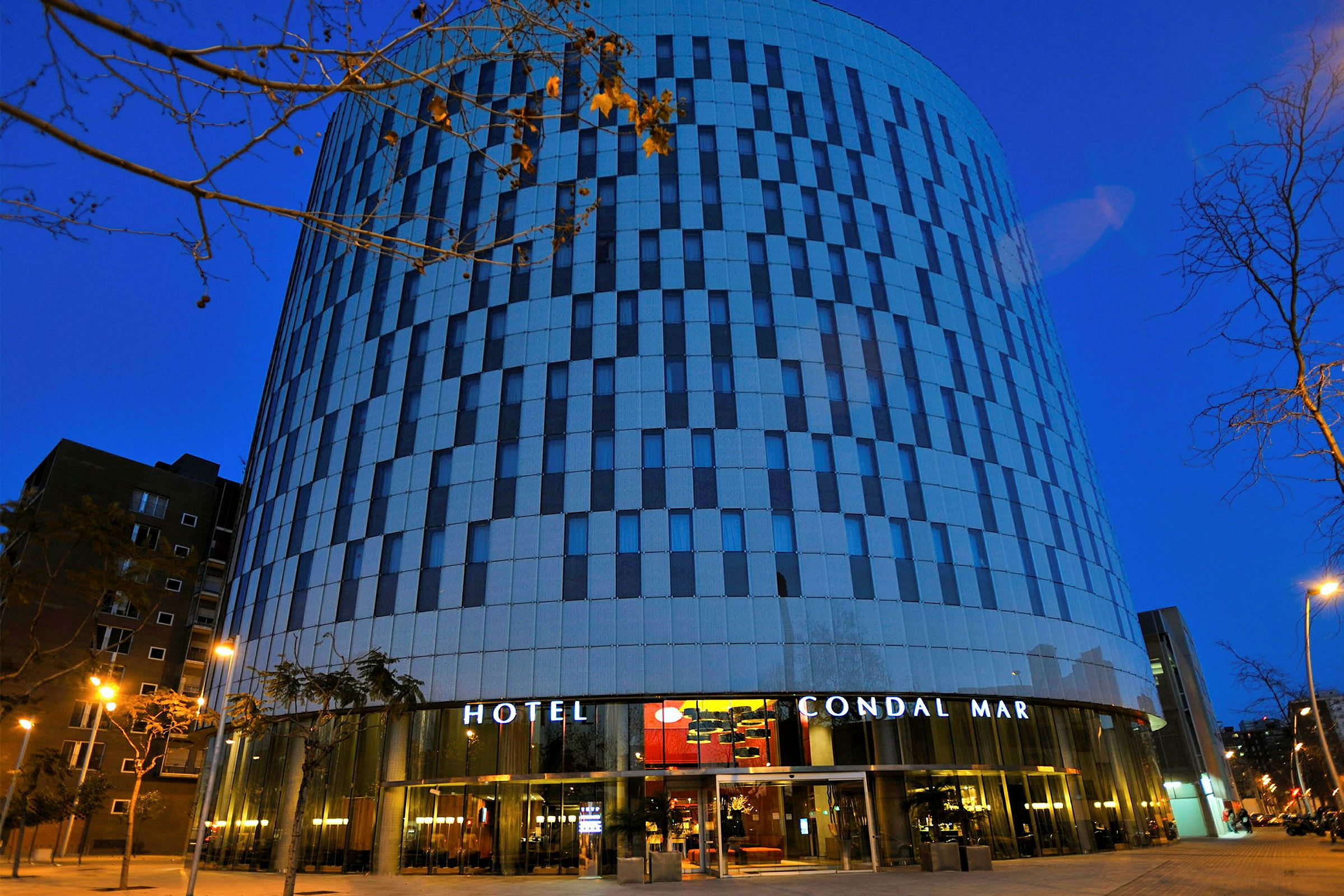 Et hotel med moderne arkitektur og en facade i striber af glas og beton fotograferet i tusmørket. (AI-genereret tekst)