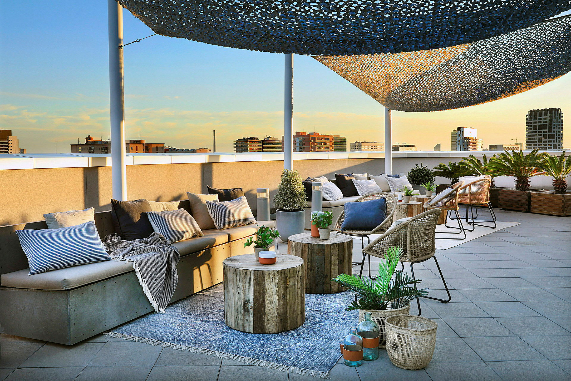En tagterrasse med siddepladser, borde og kurve dekoreret med planter og puder er afbildet. (AI-genereret tekst)