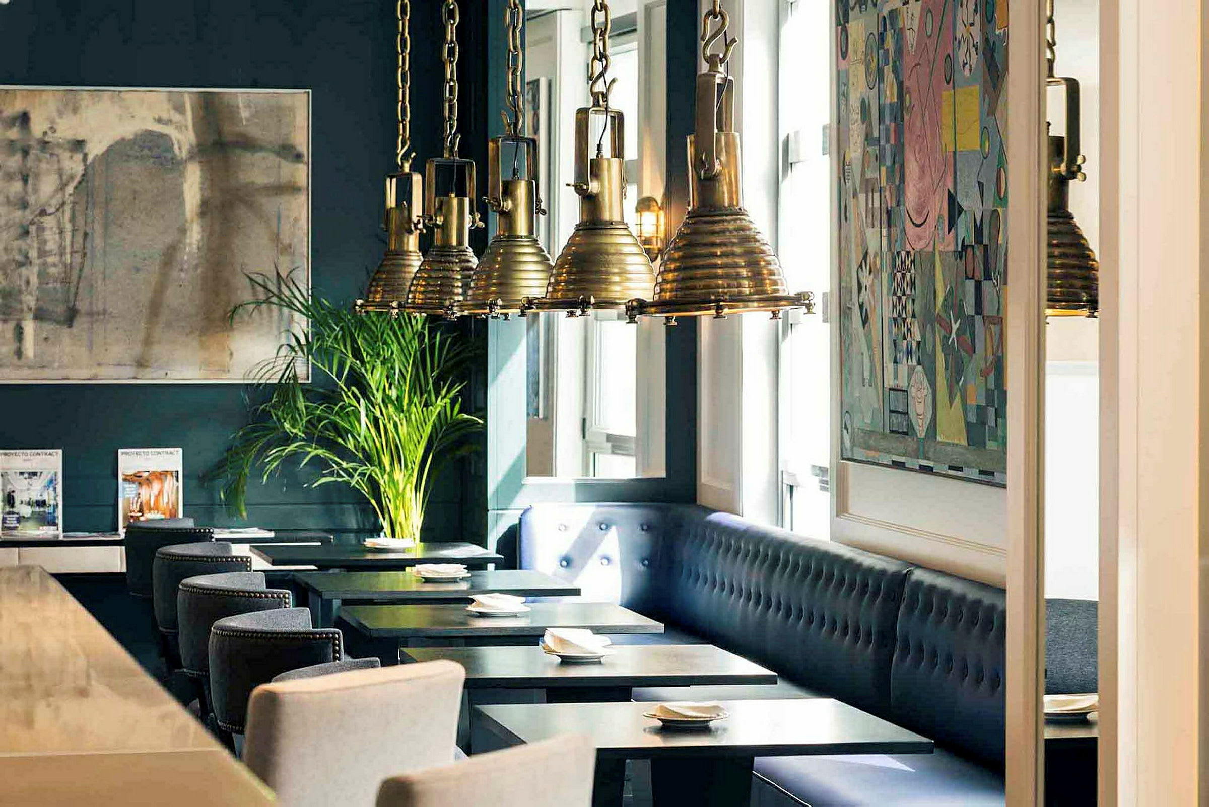 Interiør af en restaurant med mørkeblå vægge, kunstværker, hængende lamper og siddepladser ved borde. (AI-genereret tekst)