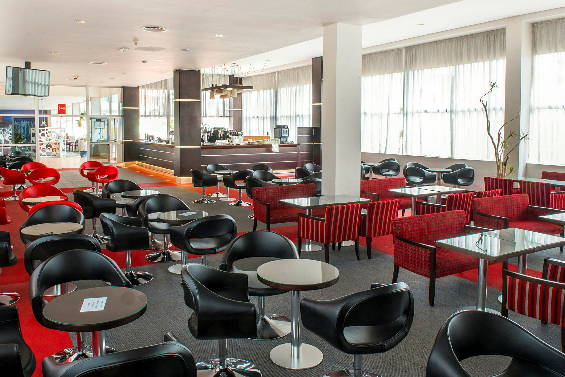 Et moderne café- eller barområde med sorte og røde stole og små borde. (AI-genereret tekst)