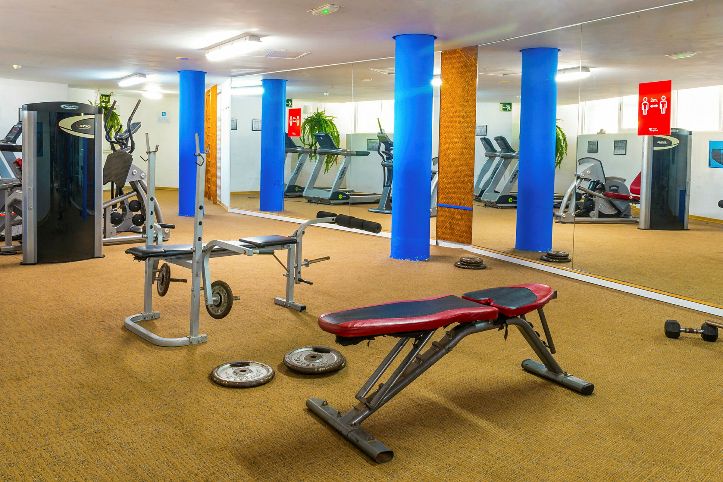 Et træningscenter med fitnessudstyr, bænke og spejle. (AI-genereret tekst)