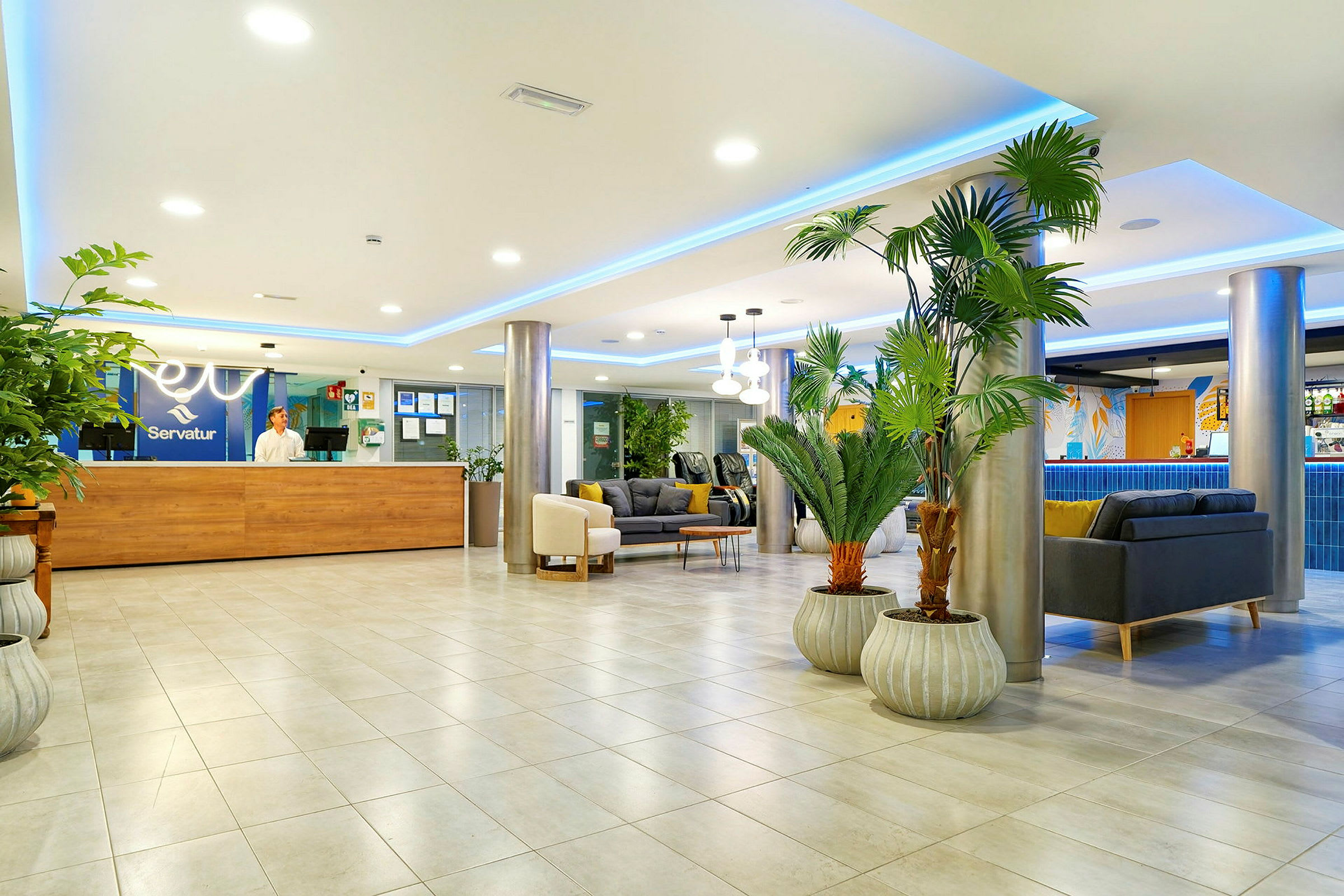 Et moderne hotellobbyområde med siddegrupper, planter og en receptionsskranke. (AI-genereret tekst)