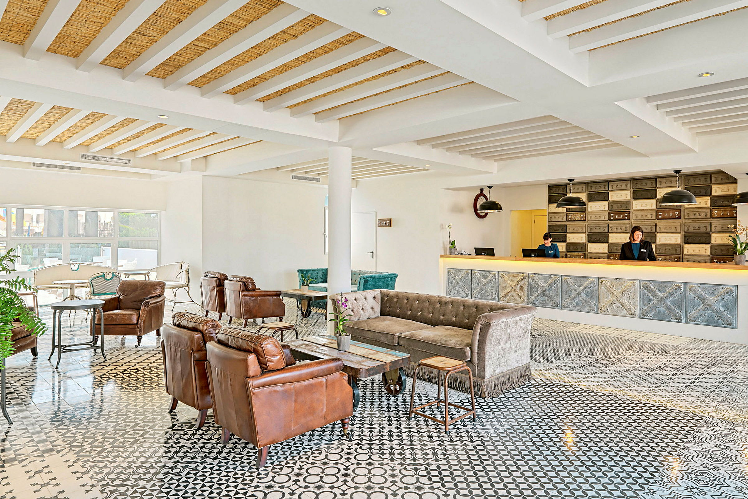 Hotellobby med komfortable siddeområder, reception og dekorativt gulv. (AI-genereret tekst)