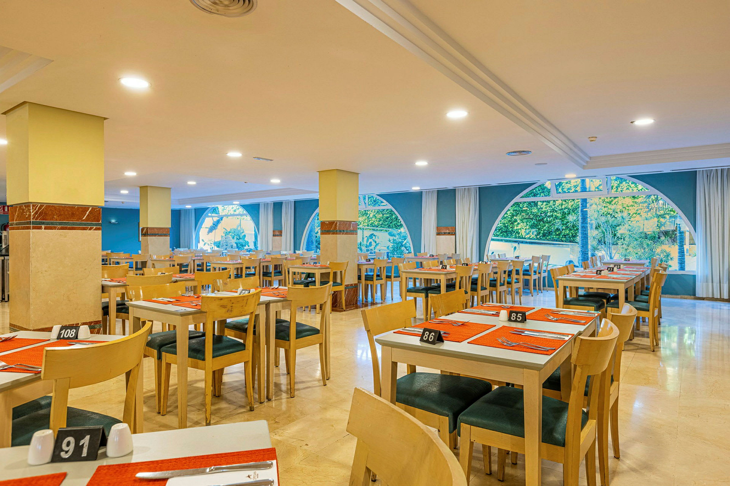 Indendørs af en restaurant med opdukkede borde og store vinduer. (AI-genereret tekst)