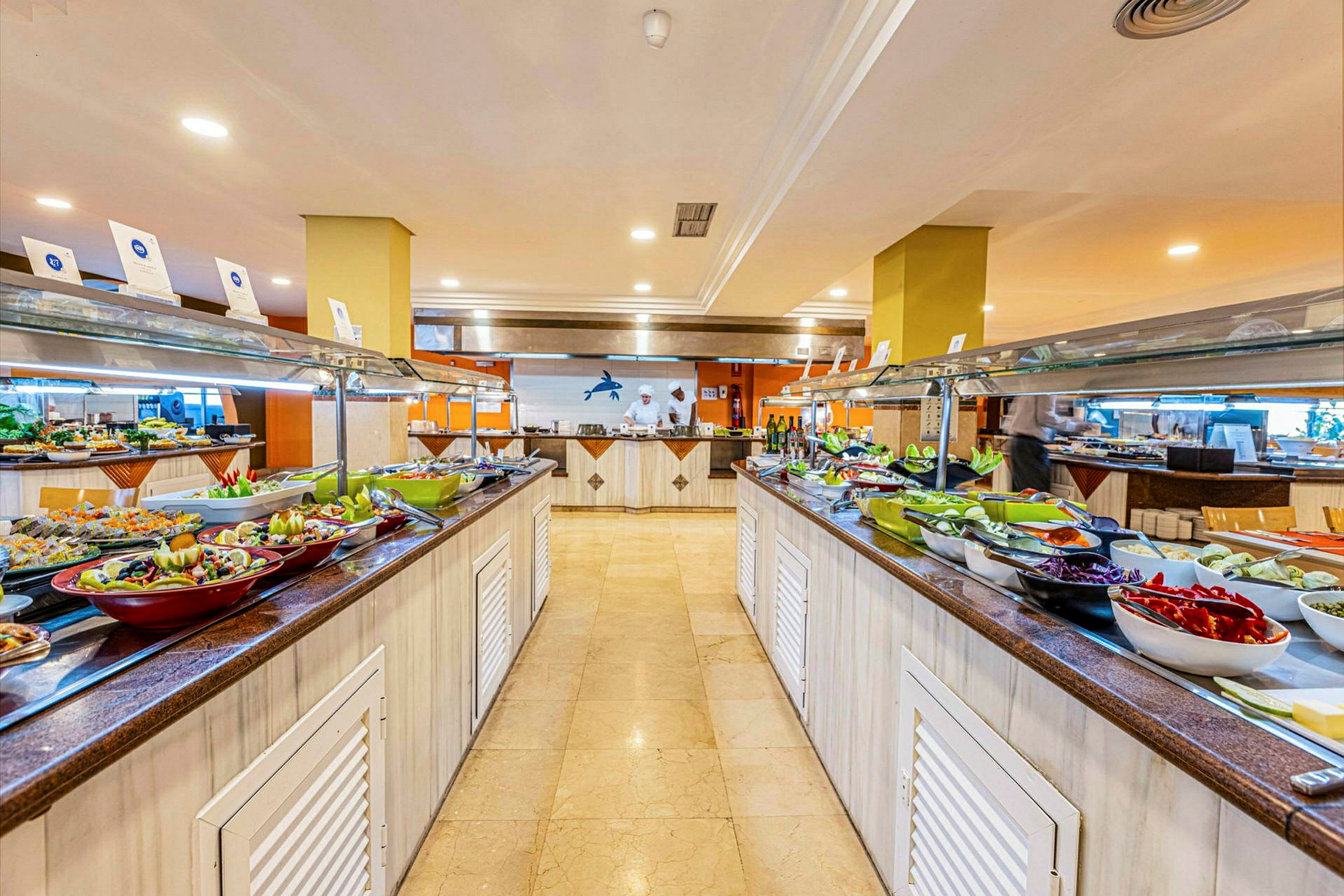 Buffet med forskellige retter og salater opstillet på to langborde indendørs. (AI-genereret tekst)