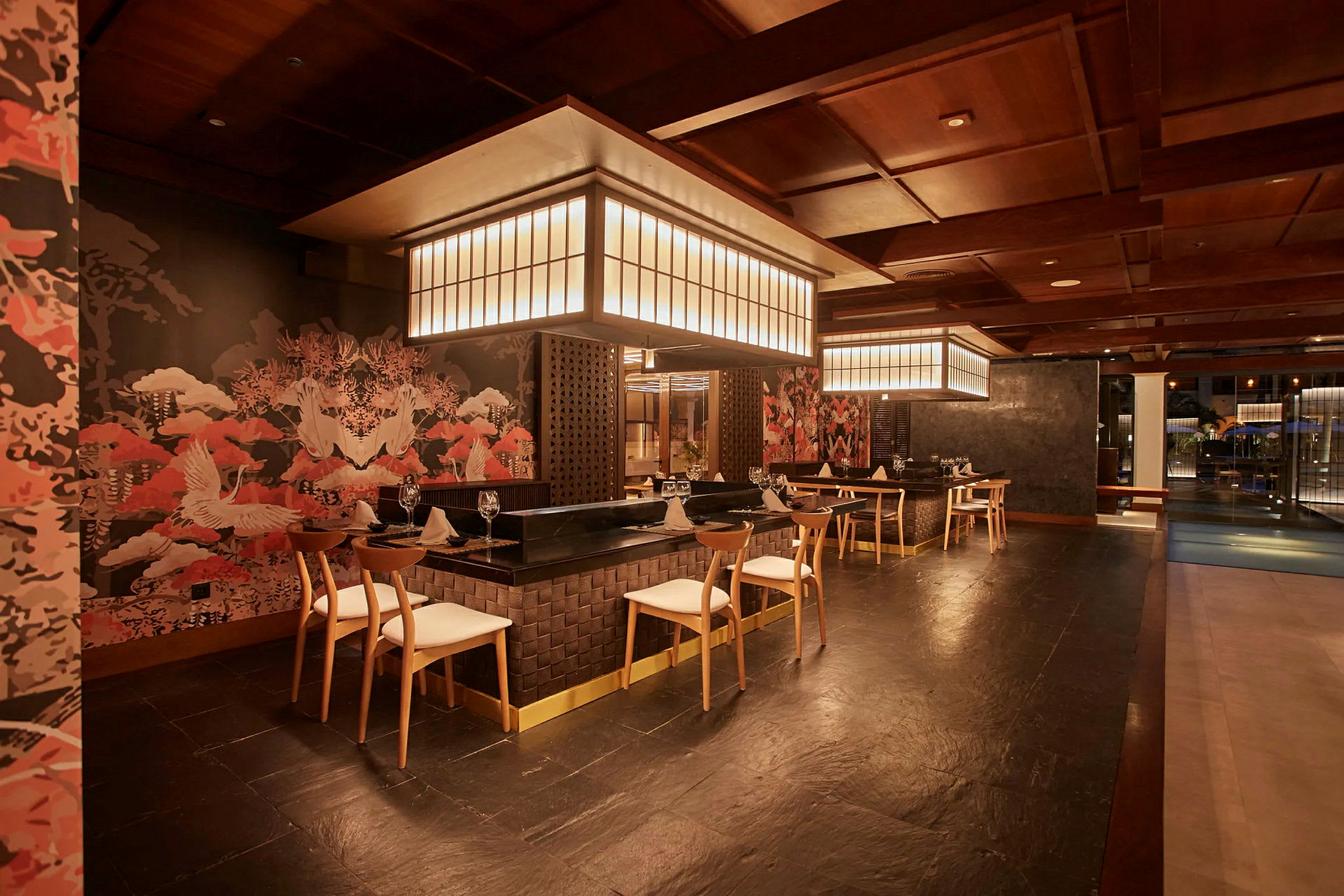 En interiør fra en elegant restaurant med moderne møbler, stilfuld belysning og vægge dekoreret med orientalsk-inspireret kunst. (AI-genereret tekst)
