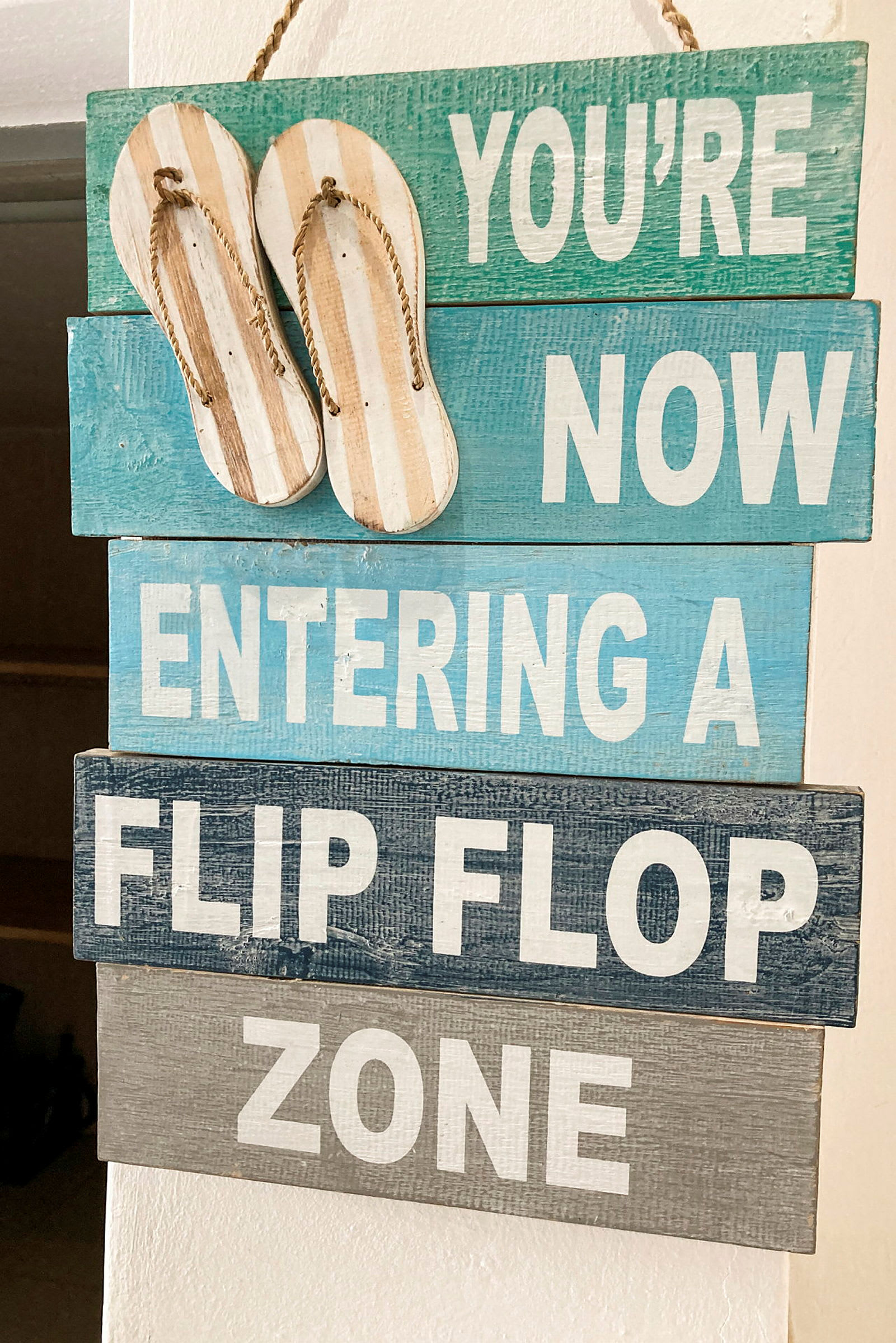 Et skilt med teksten 'You're now entering a flip flop zone' og to hængende sandaler øverst. (AI-genereret tekst)