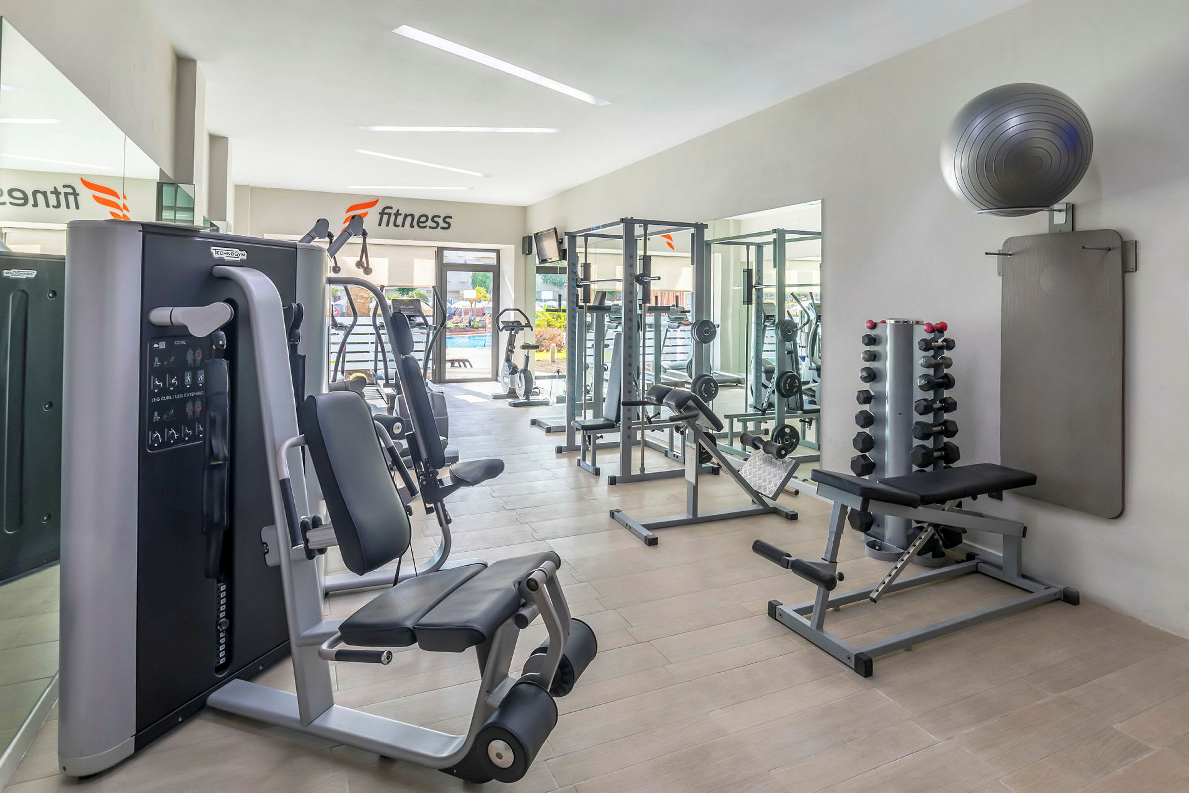 Billede af et lyst fitnesscenter med træningsudstyr og vægte. (AI-genereret tekst)