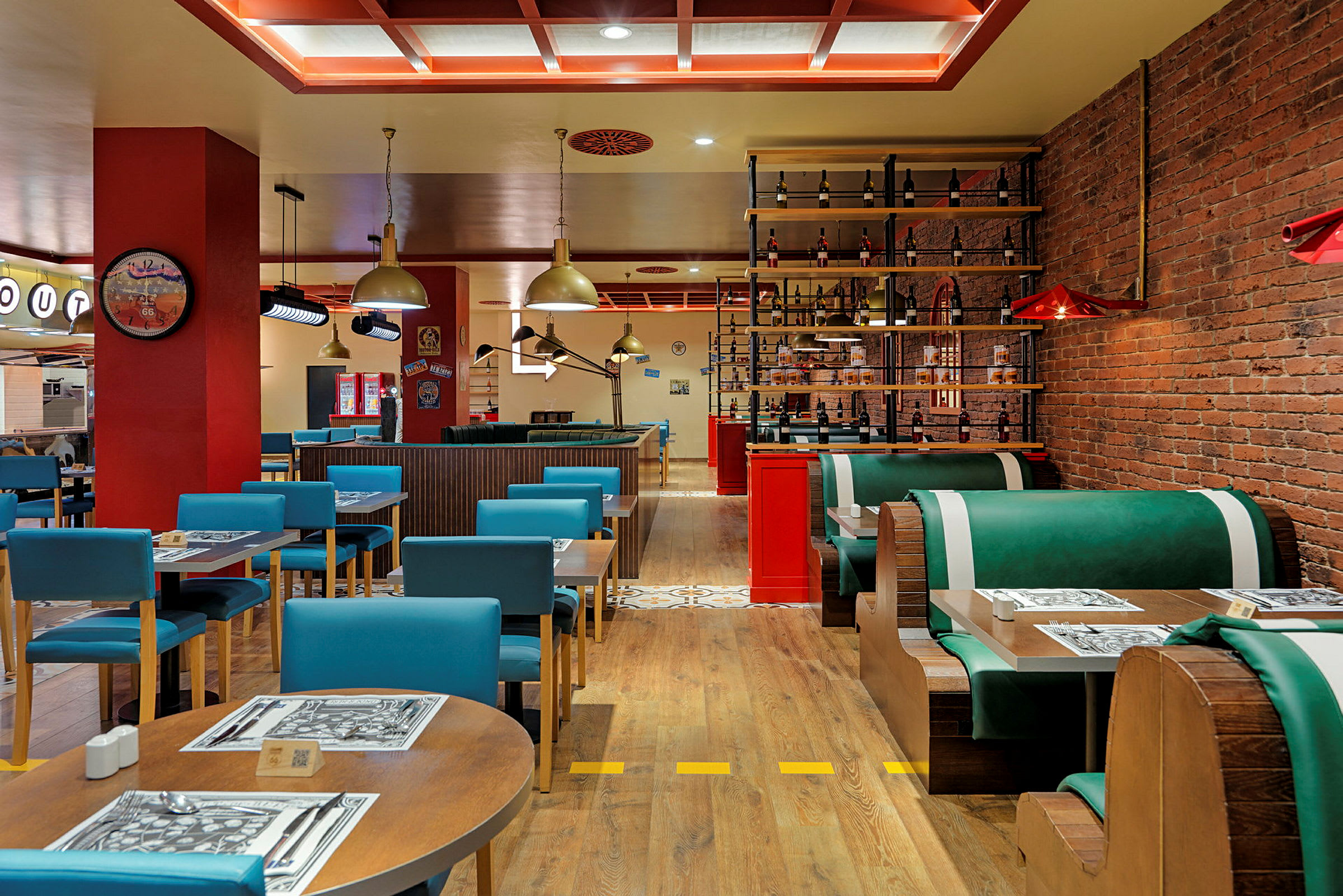 Indretningen i en restaurant med borde og stole samt båse med grønne sofaer. (AI-genereret tekst)