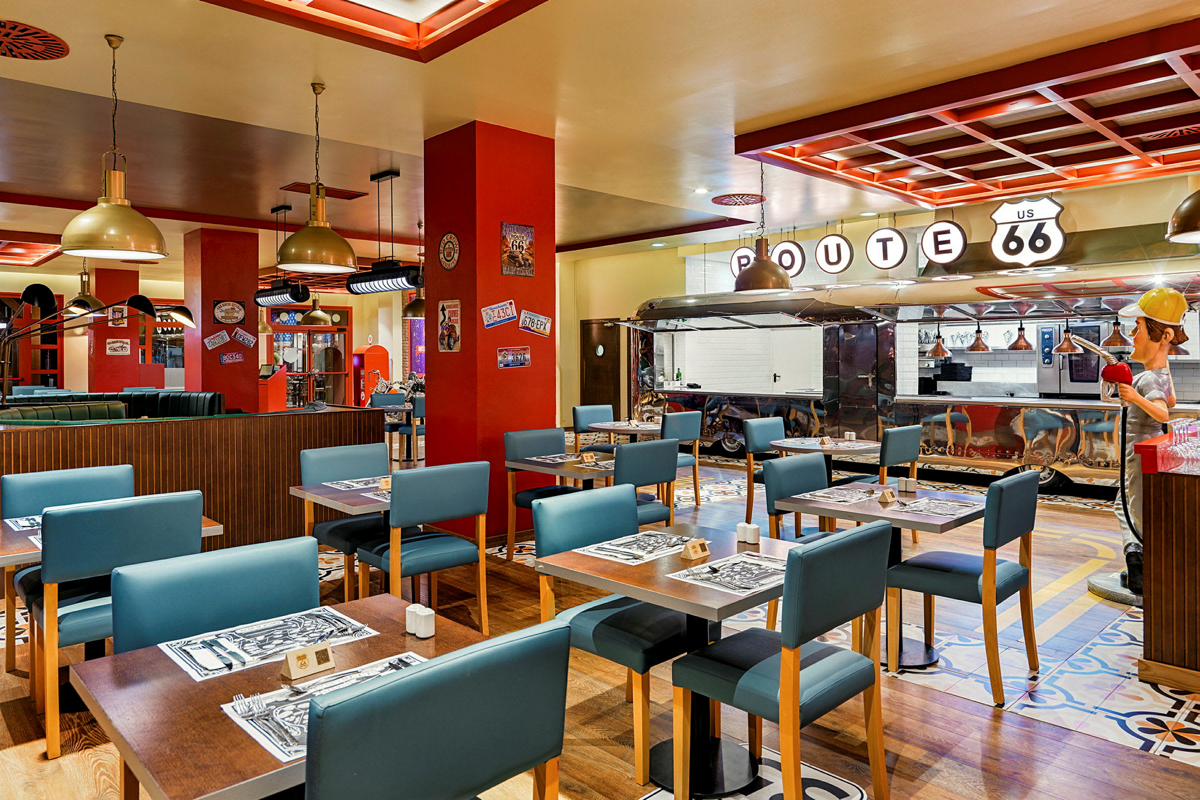 En restaurant indrettet i amerikansk Route 66-stil med borde, blå stole og en serveringsdisk. (AI-genereret tekst)