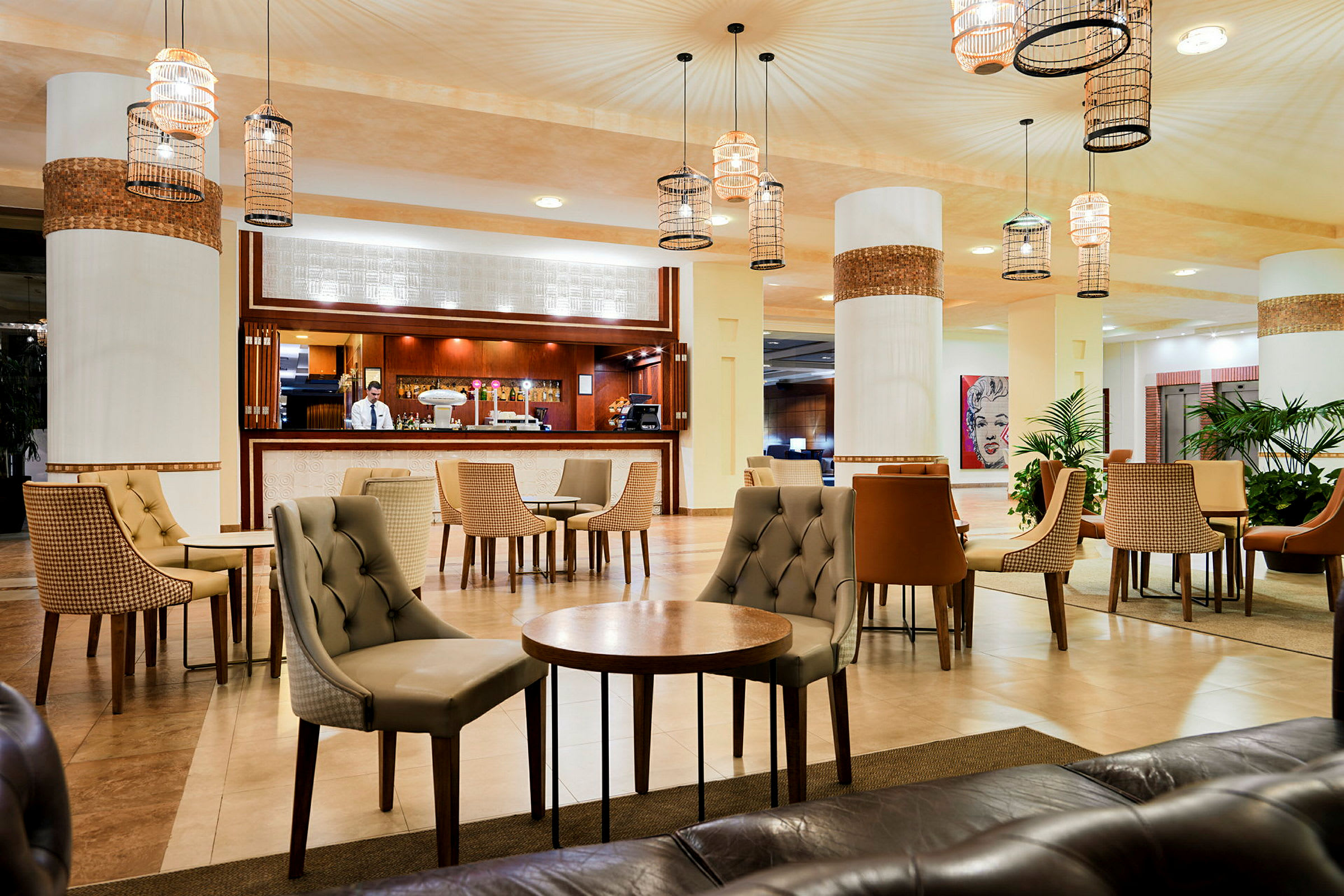 Elegant hotellets lobby med møblerede siddegrupper og en bemandet receptionsskranke. (AI-genereret tekst)