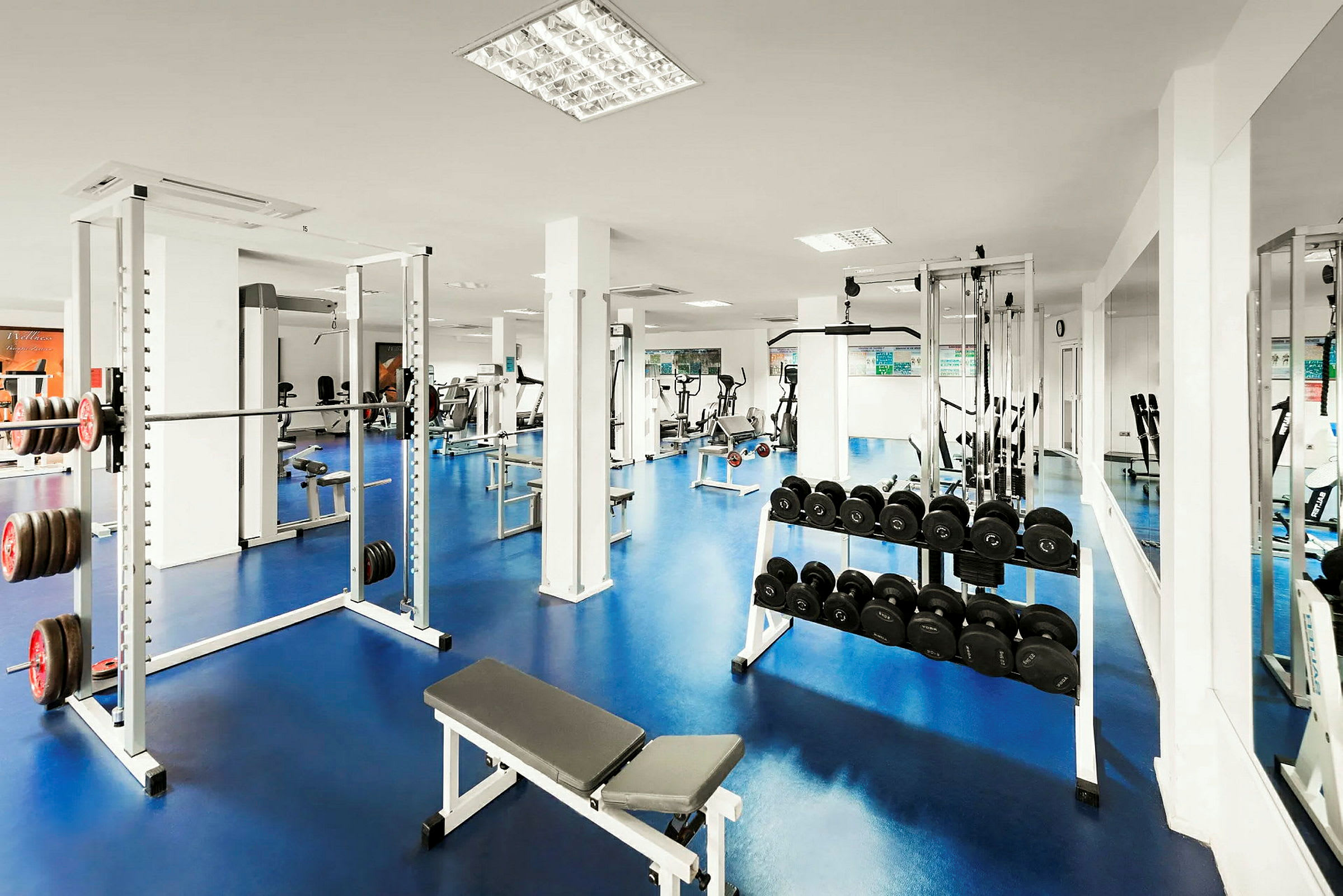 Et træningscenter med forskellige fitnessudstyr såsom vægte, håndvægte og træningsmaskiner. (AI-genereret tekst)