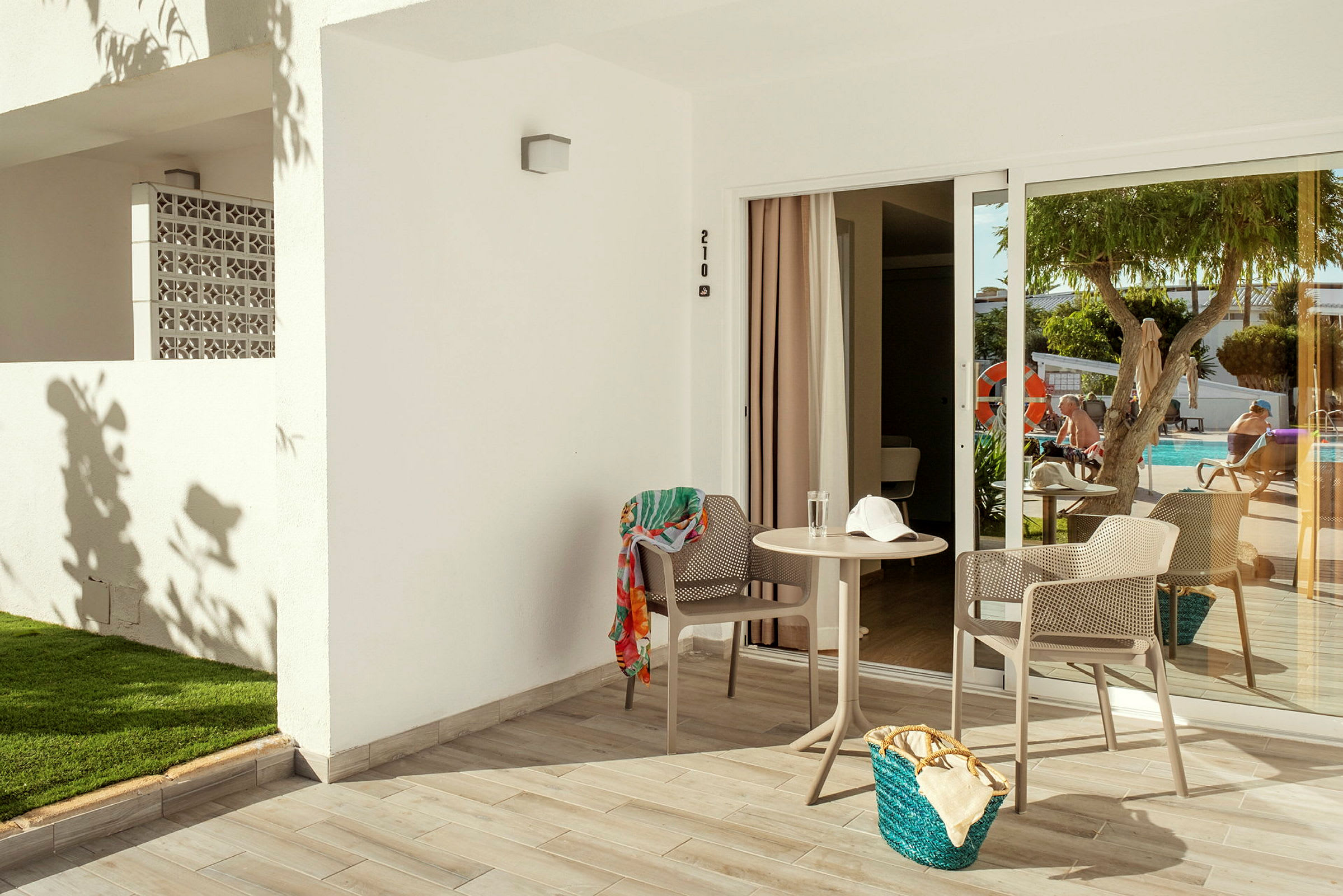 En terrasse med to stole, et lille bord og en swimmingpool i baggrunden. (AI-genereret tekst)