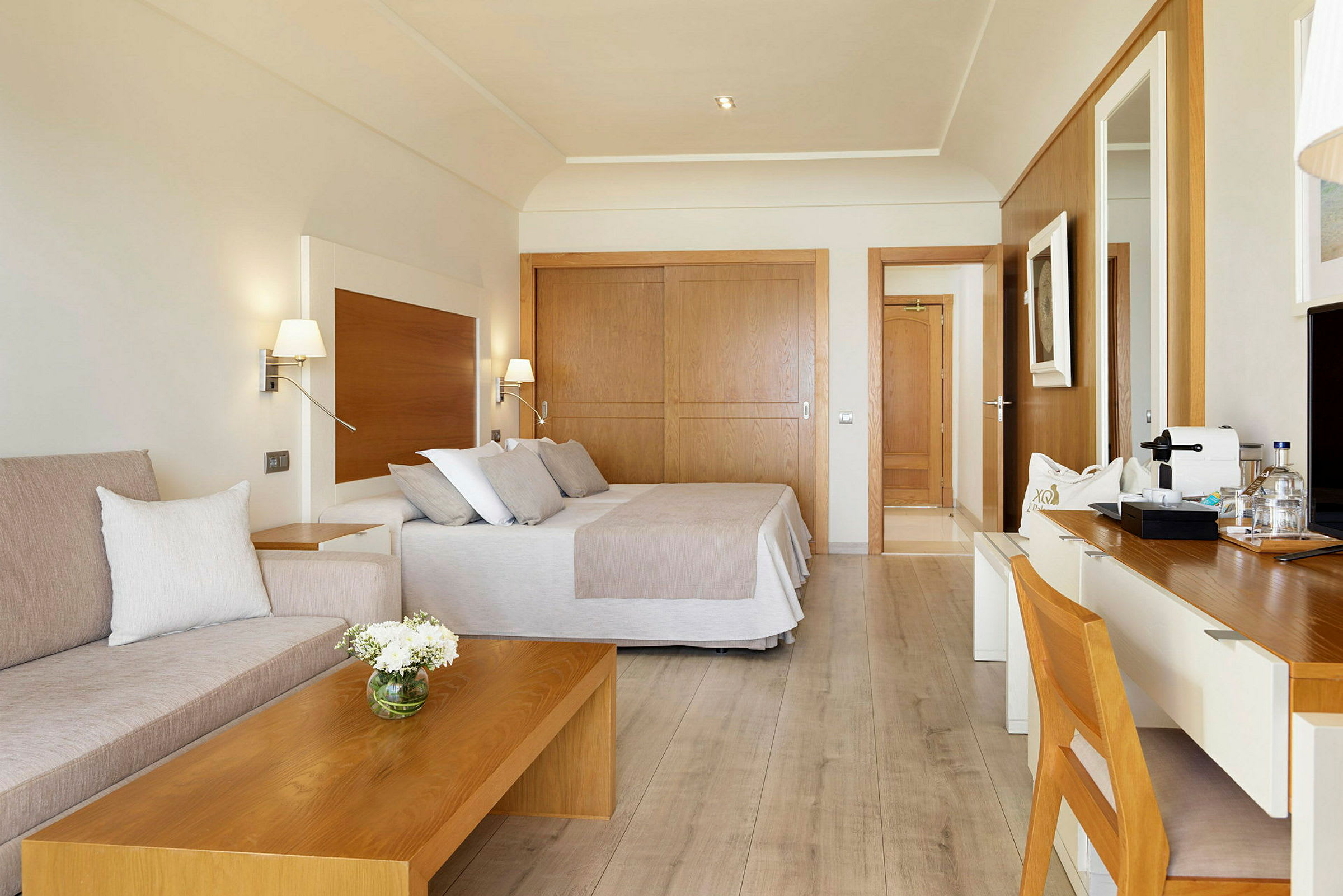 Et hotelværelse med moderne indretning, seng, siddeområde og skrivebord. (AI-genereret tekst)