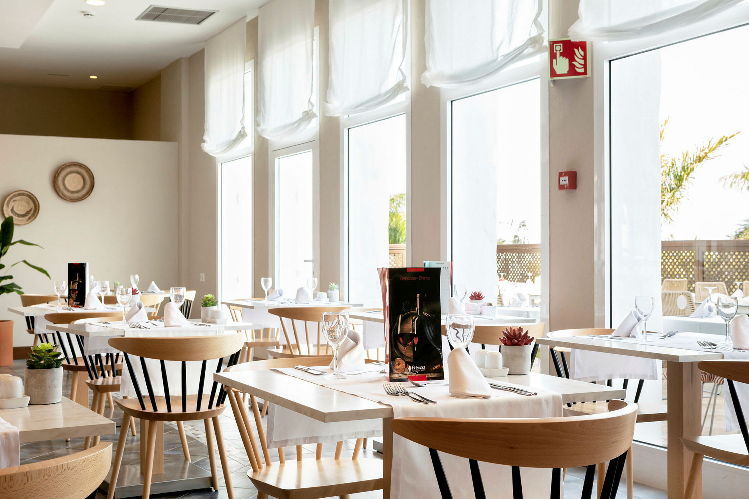 En lys og moderne restaurant med borde og stole, indrettet med hvide duge og glas. (AI-genereret tekst)