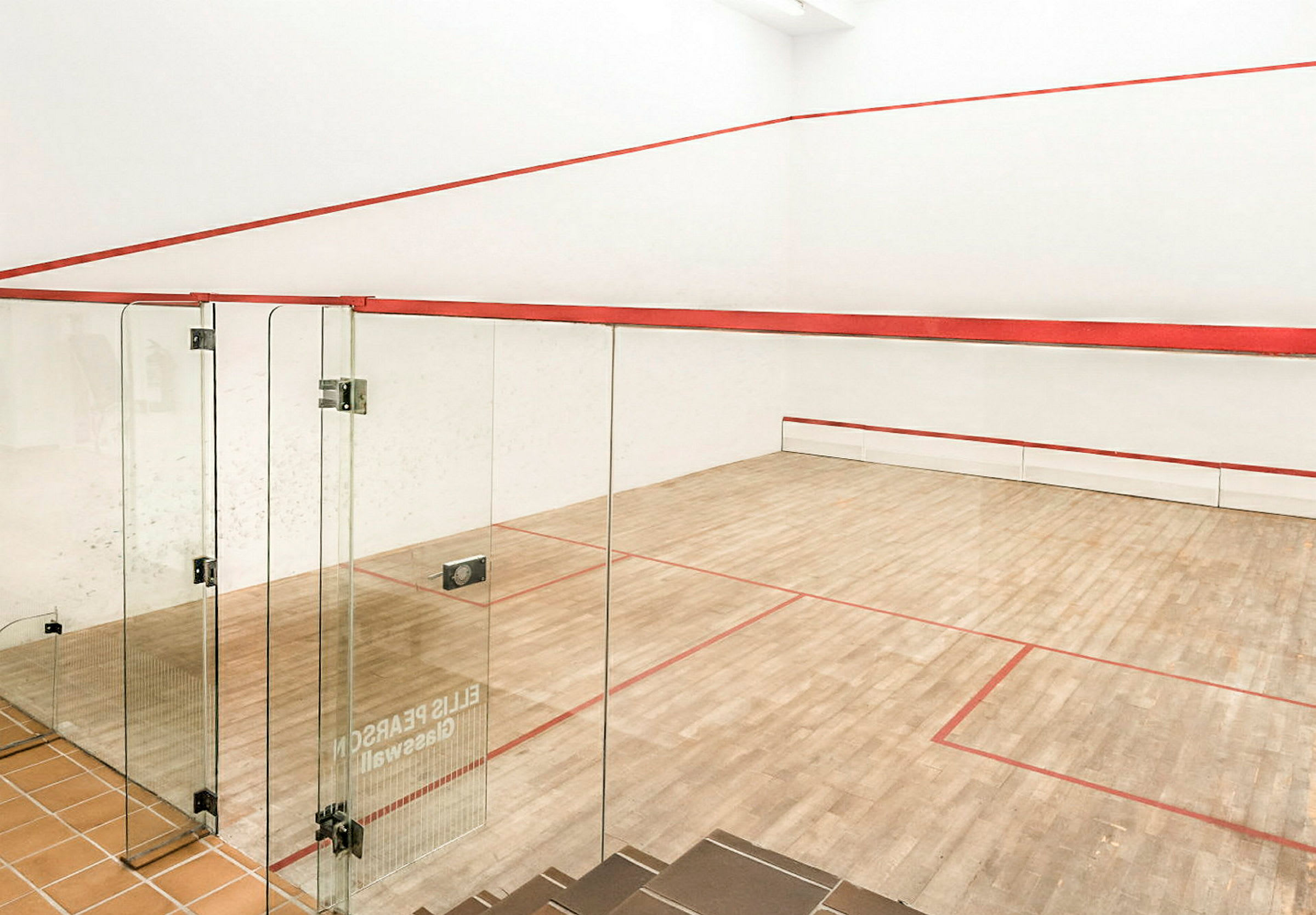En squashbane med trægulv og glasvægge. (AI-genereret tekst)