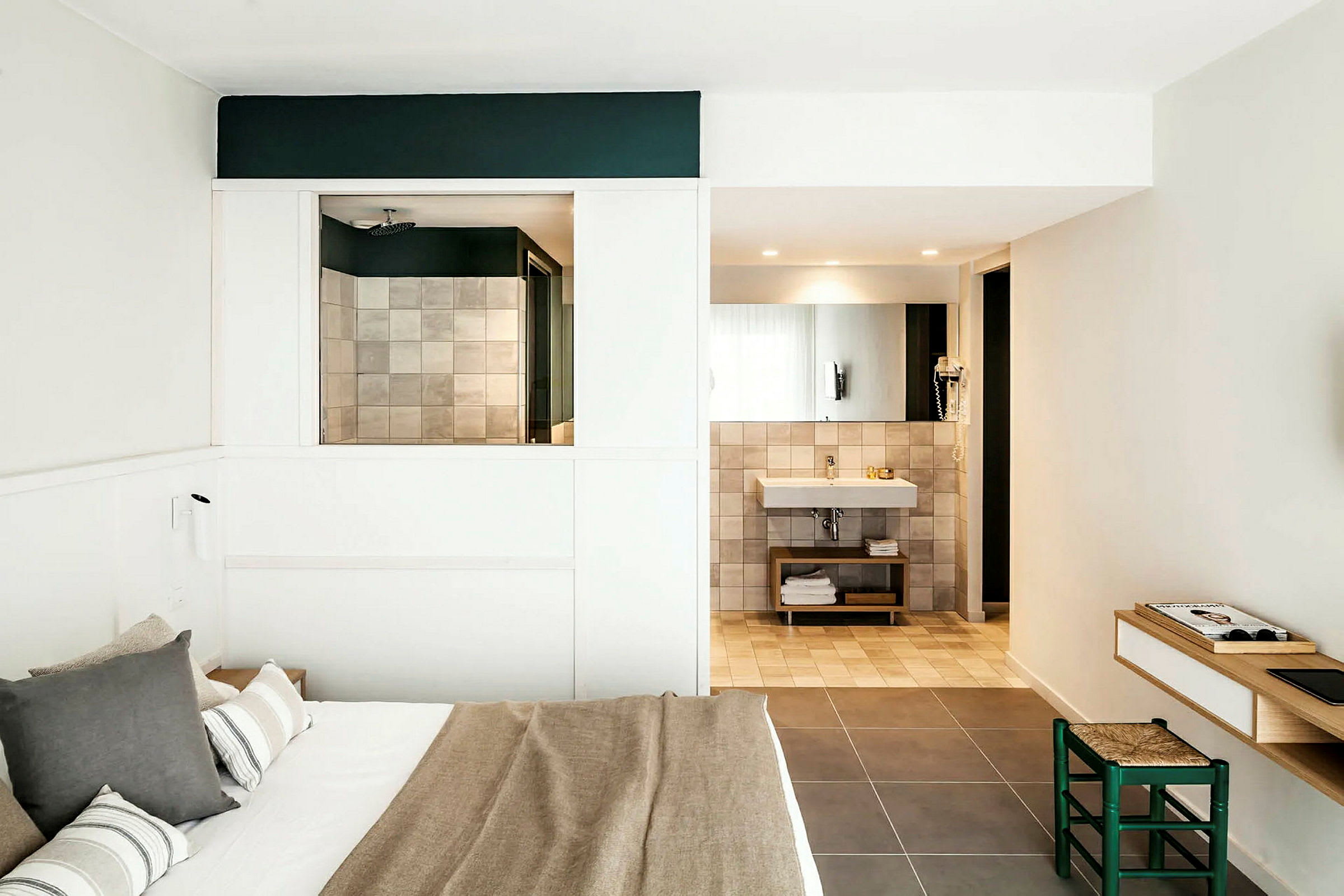 Et moderne hotelværelse med en dobbeltseng, badeværelse med spejl og håndvask samt en lille arbejdsplads med stol. (AI-genereret tekst)