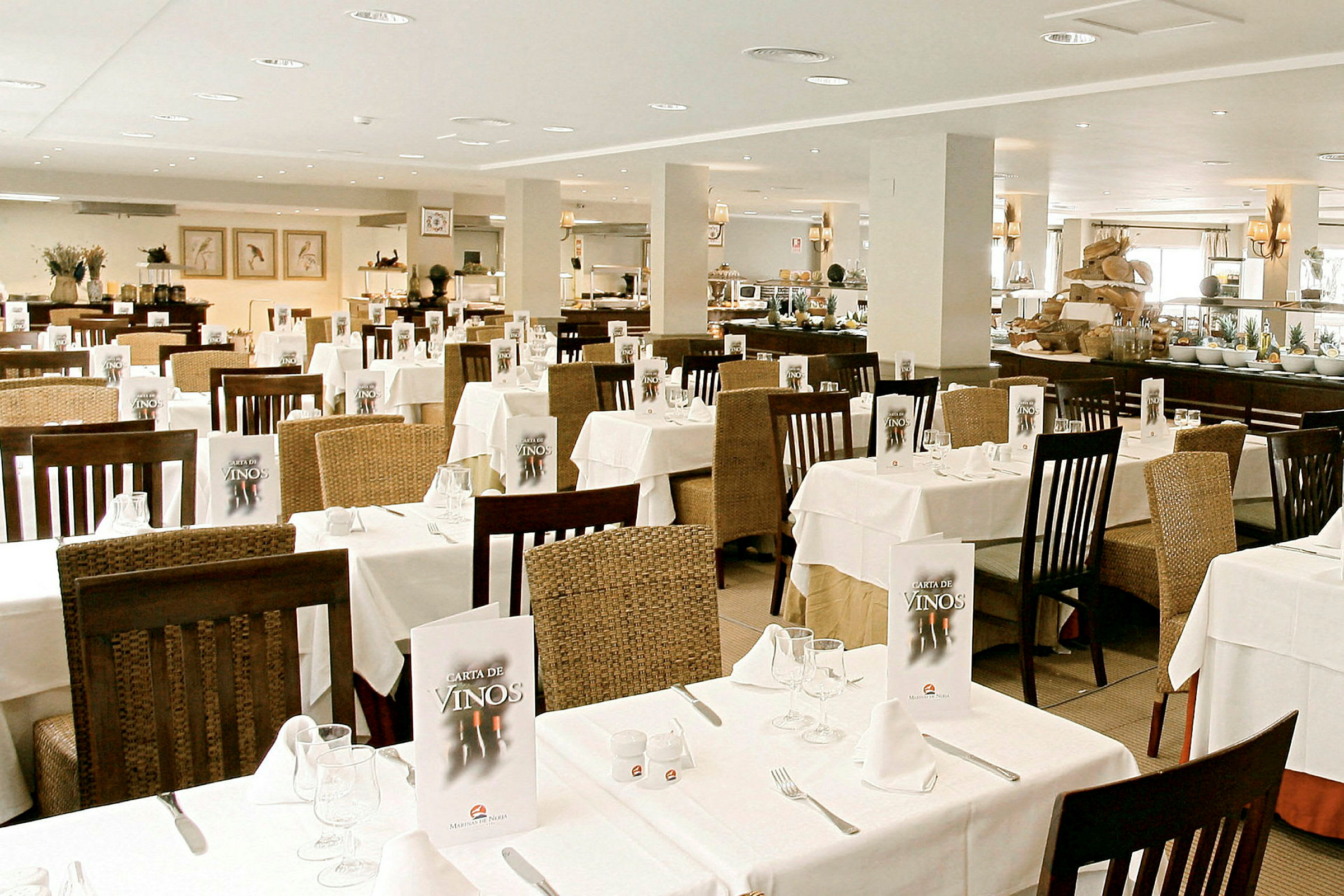 En lys restaurant med dækkede borde og stole, menuer på bordene og en buffet i baggrunden. (AI-genereret tekst)