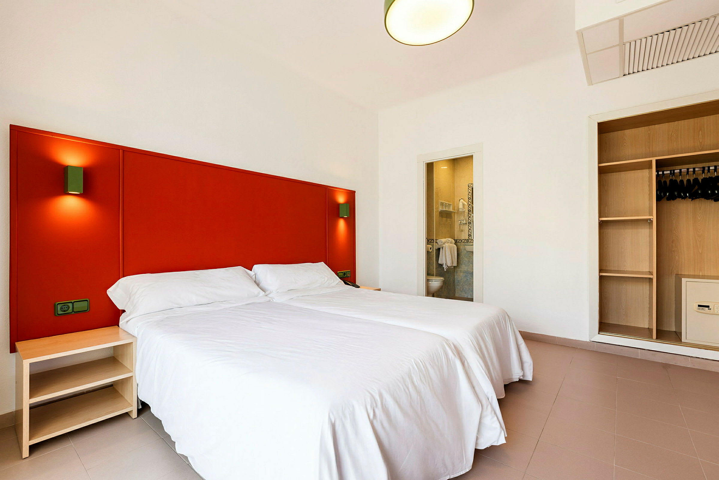 Hotelværelse med to enkeltsenge, et skab og et åbent badeværelse. (AI-genereret tekst)