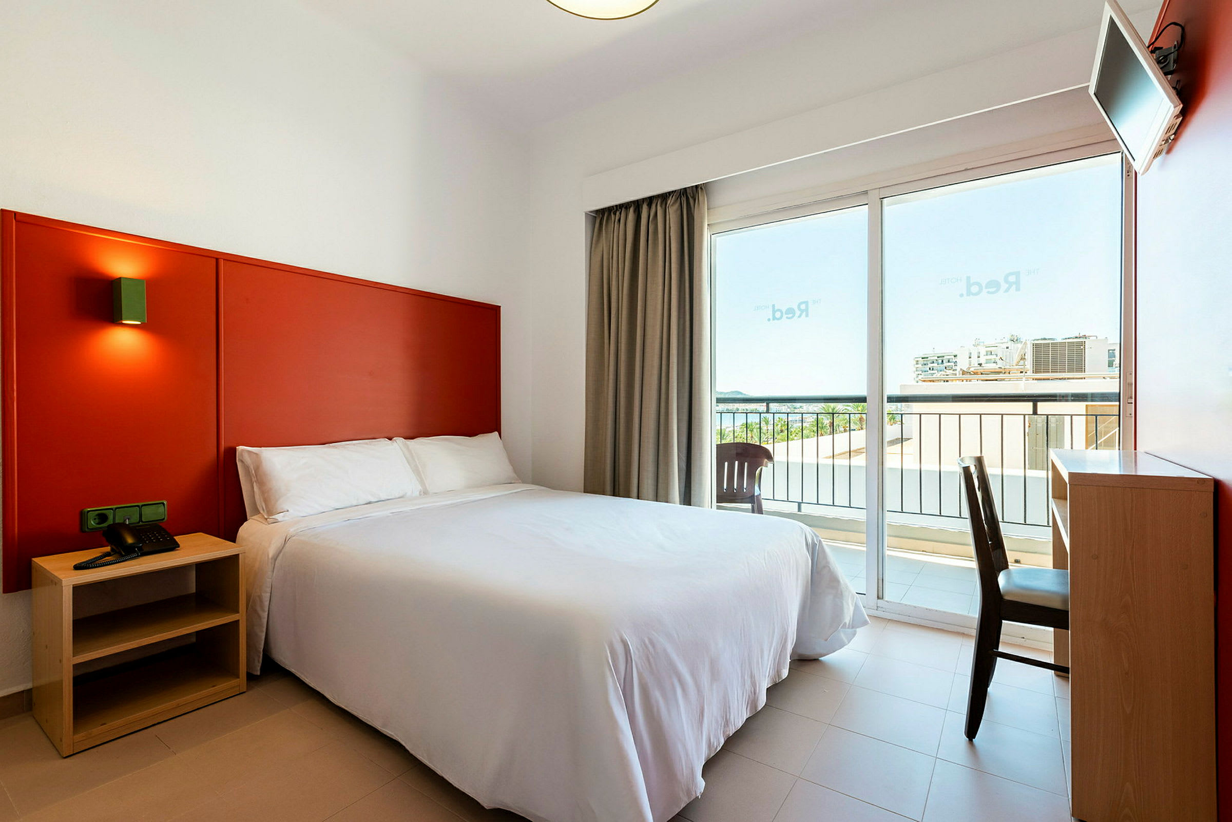 Hotelværelse med en dobbeltseng, skrivebord og altan. (AI-genereret tekst)