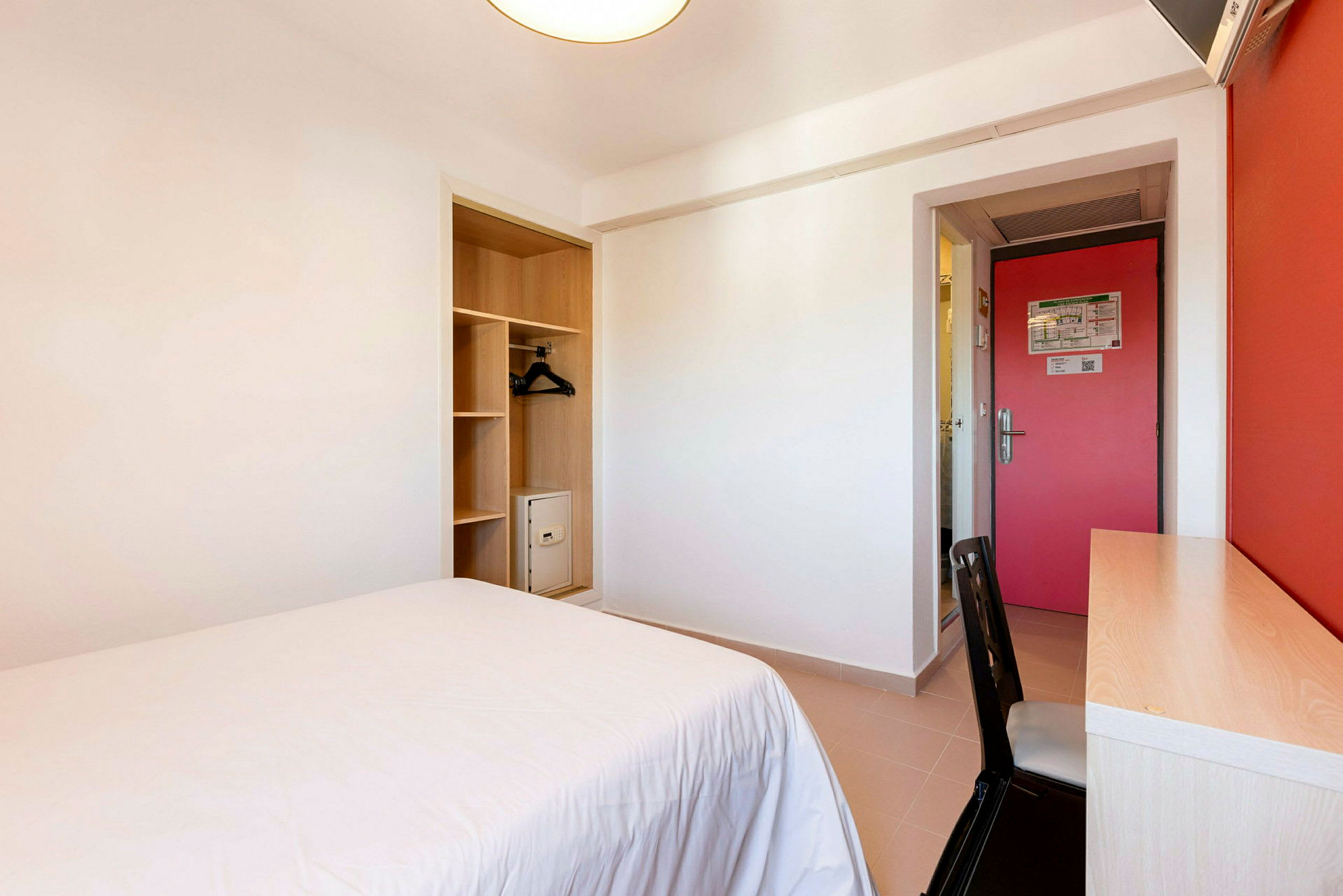 Et hotelværelse med en seng, skrivebord og garderobe. (AI-genereret tekst)