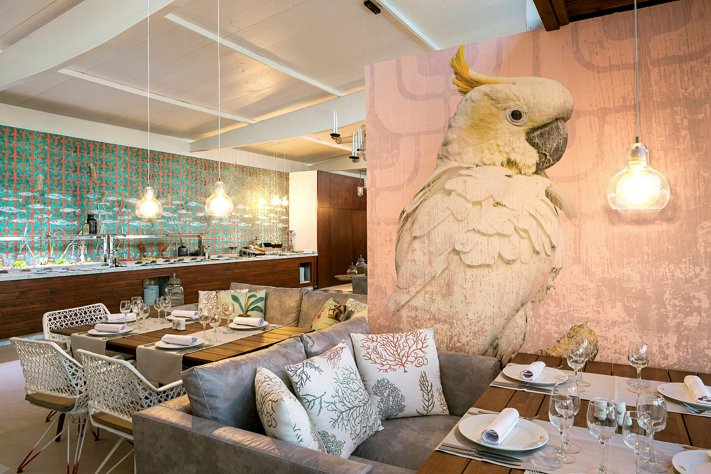 En elegant indrettet restaurant med et stort fuglemotiv, dæmpet belysning og et spiseområde med sofaer og puder. (AI-genereret tekst)