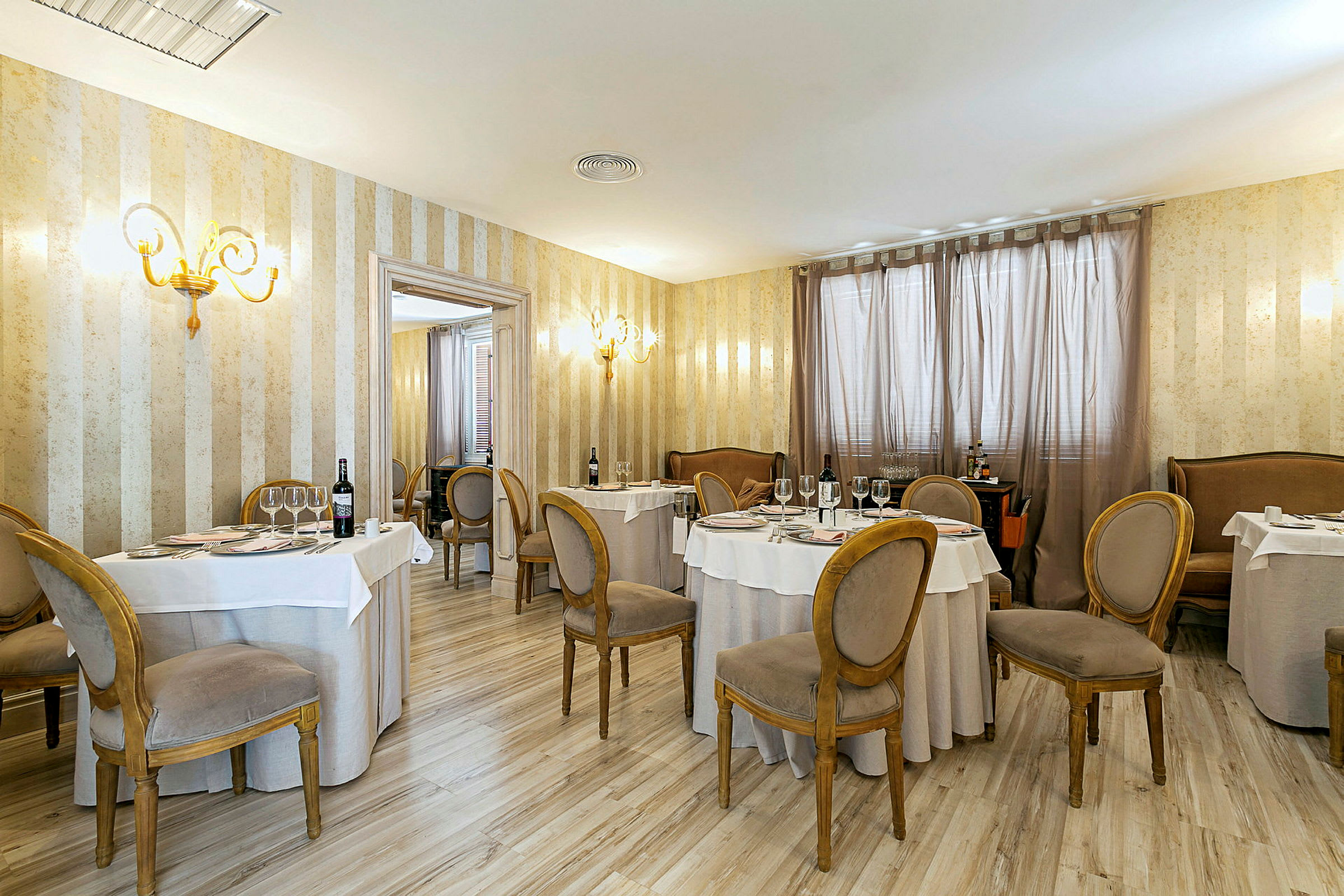 Et elegant indrettet restaurantlokale med runde dækkede borde og stole i klassisk stil. (AI-genereret tekst)