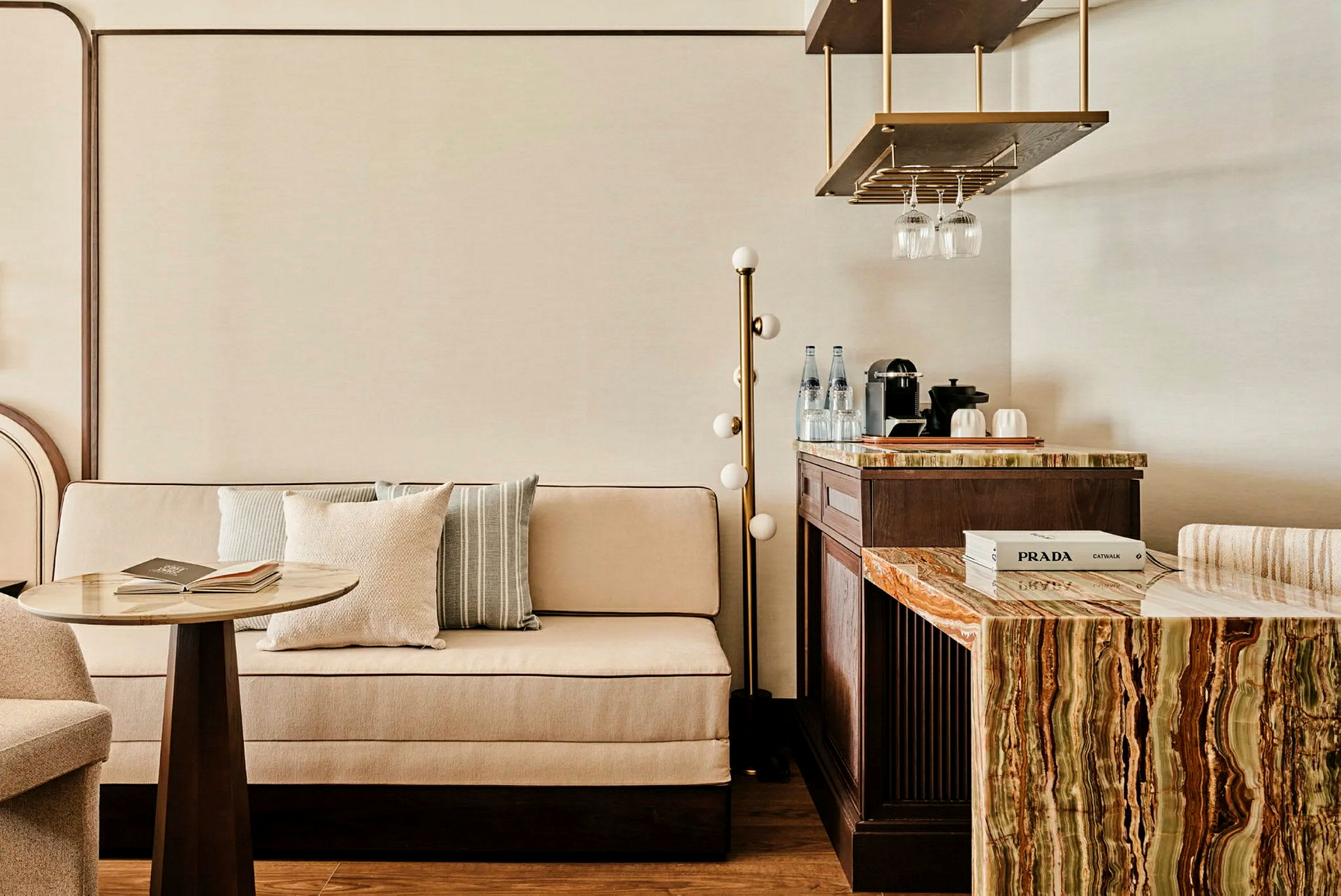 En elegant indrettet siddegruppe med en sofa, et lille bord og en bænk med en marmoreret overflade samt en kaffemaskine og glas. (AI-genereret tekst)