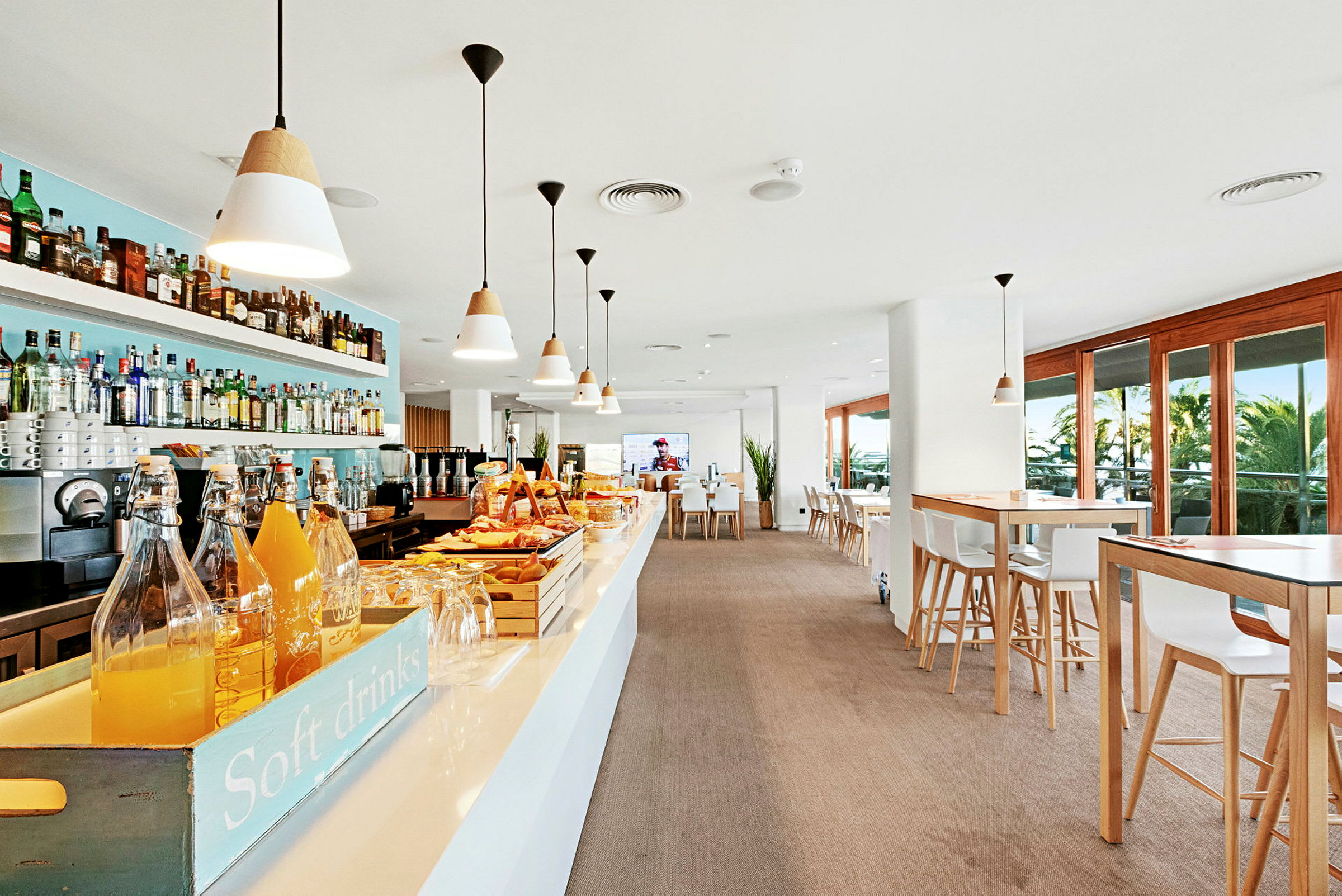 Interiørbillede af en moderne bar og café med borde, stole og store vinduer samt en serveringsdisk. (AI-genereret tekst)