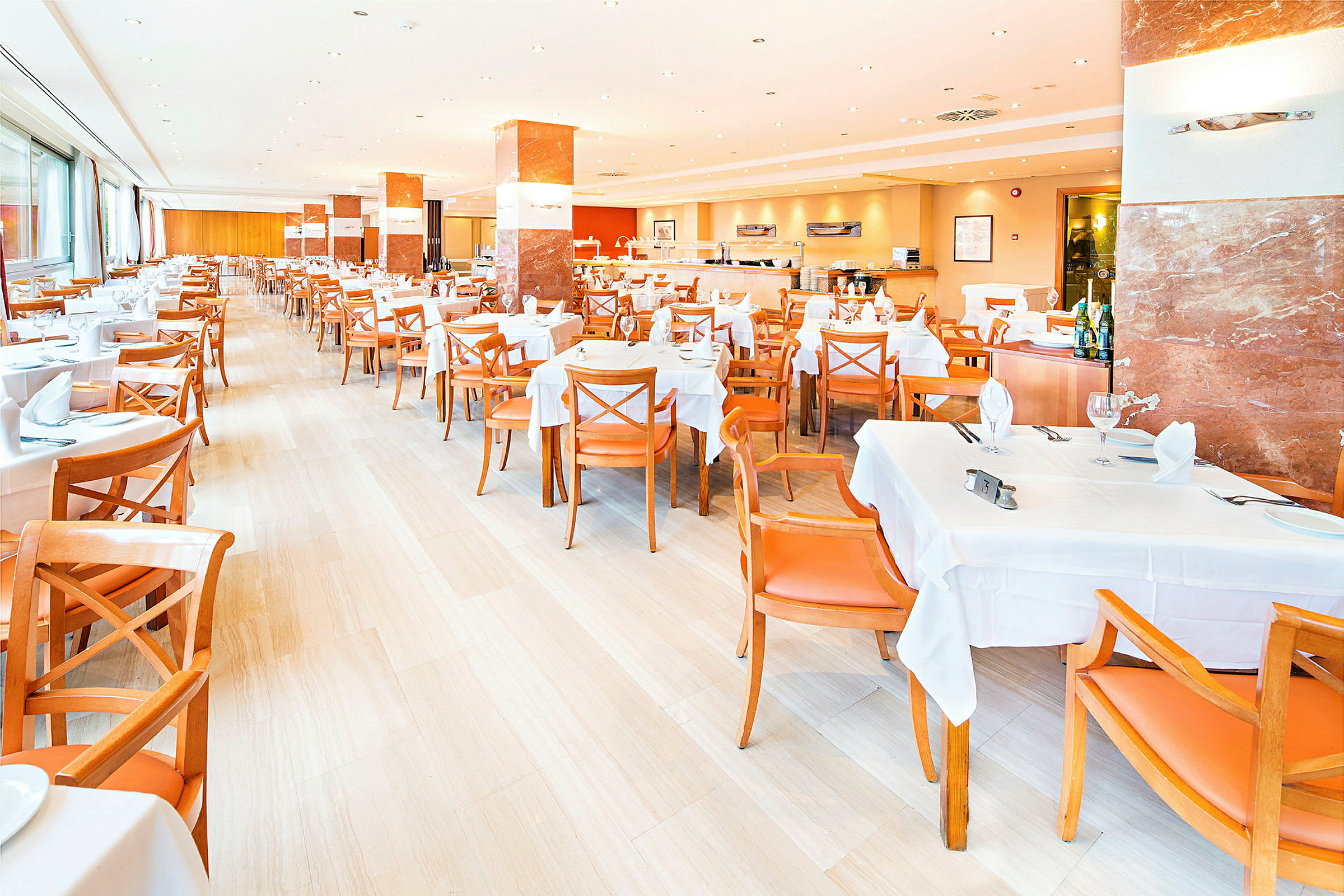 En lys restaurant med hvide duge og orange stole, klar til gæster. (AI-genereret tekst)