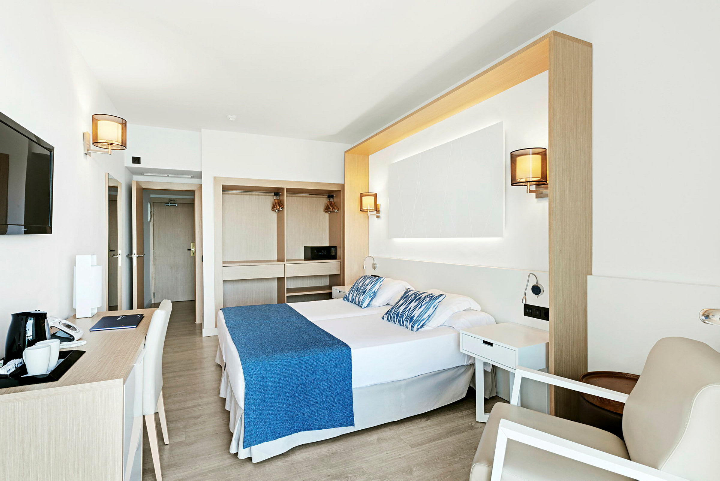 Et lyst og moderne hotelværelse med dobbeltseng, skrivebord og garderobe. (AI-genereret tekst)