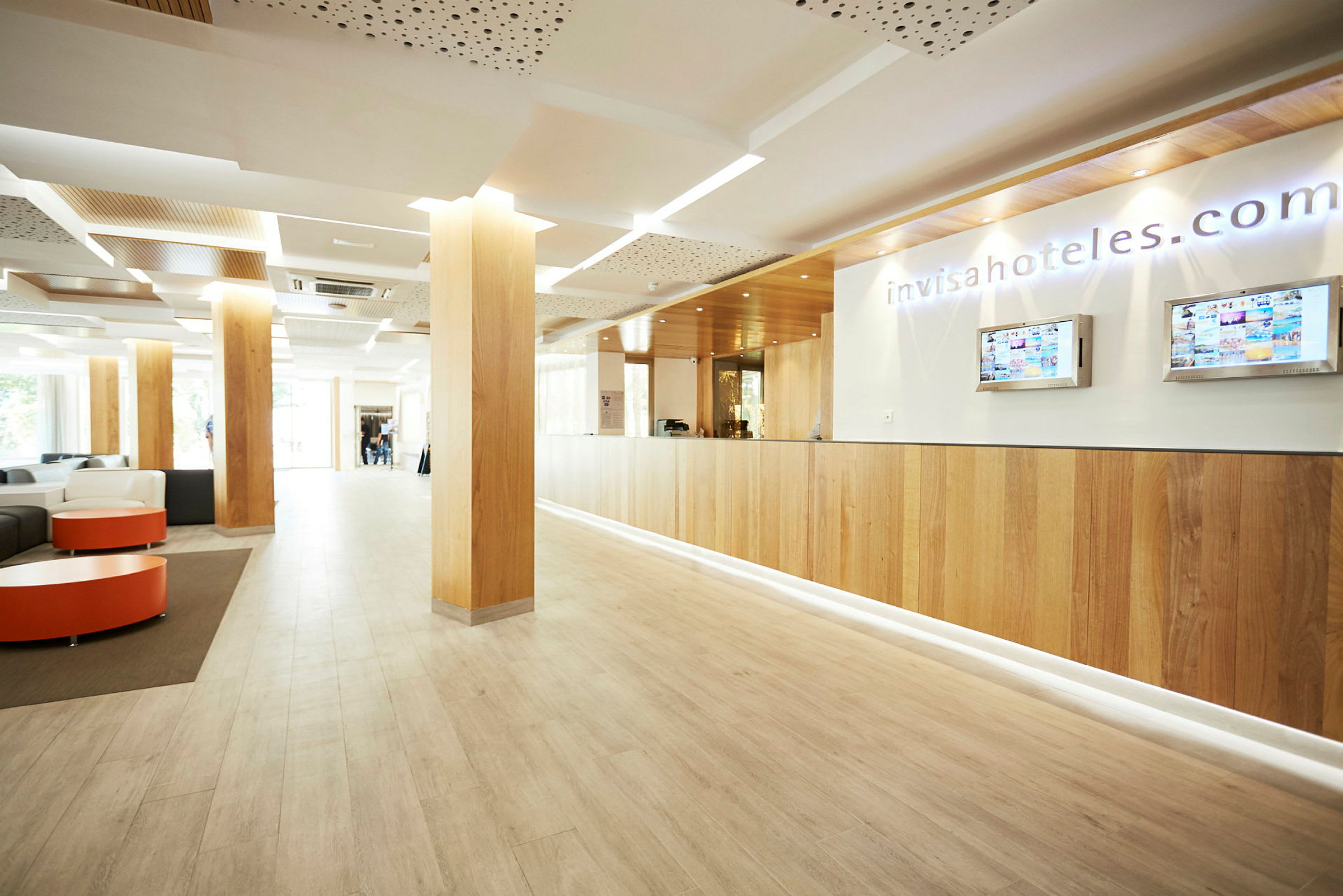 Receptionen i en moderne lobby, med trægulv og søjler samt en informationsskranke. (AI-genereret tekst)
