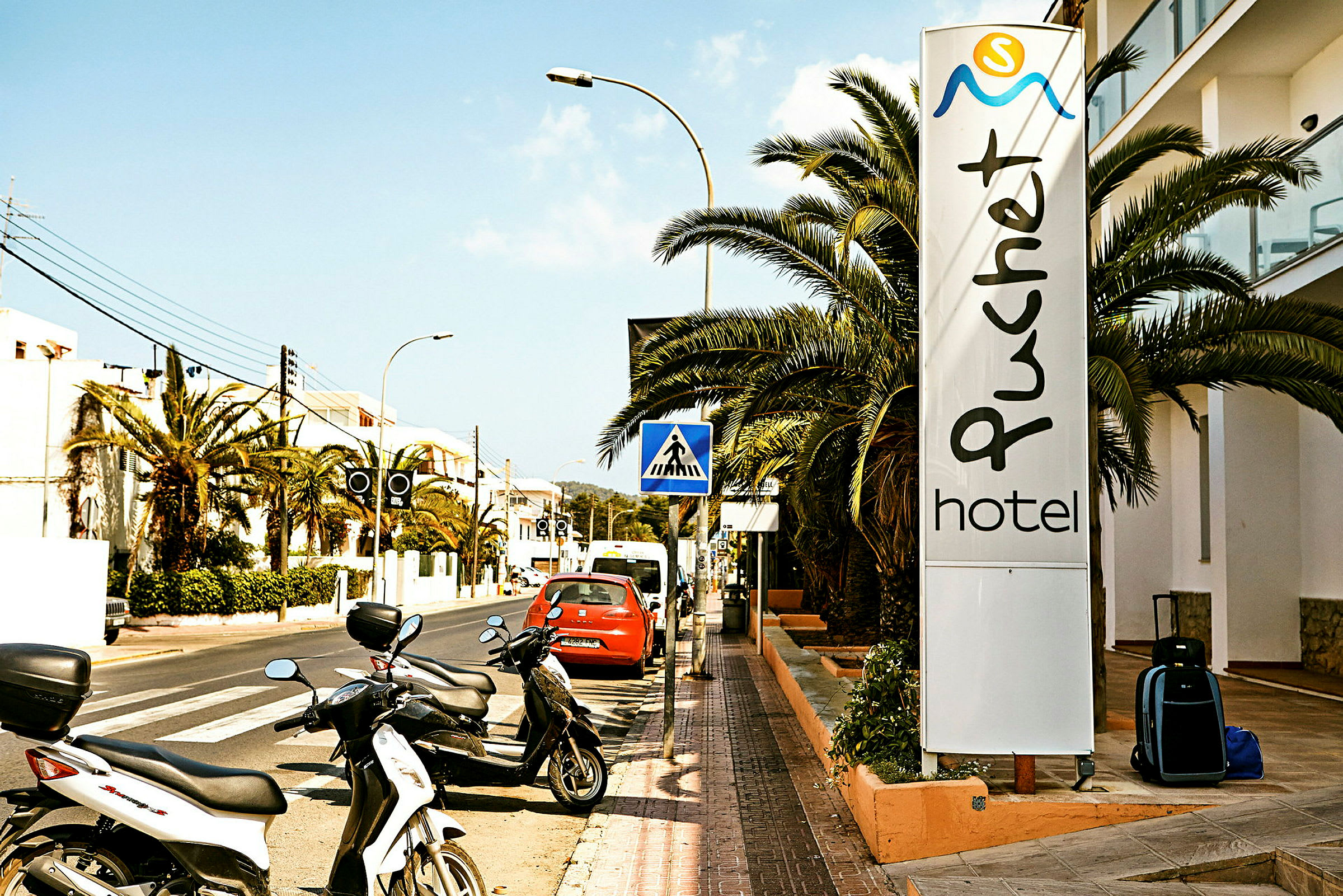 Gade med parkerede motorcykler og et skilt med teksten "Puchet Hotel". (AI-genereret tekst)