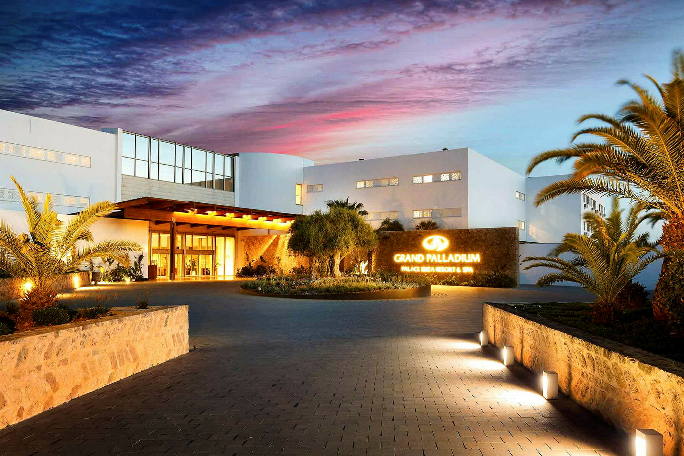 Hotel facade ved skumringen med en indbydende indgang og oplyst skilt. (AI-genereret tekst)