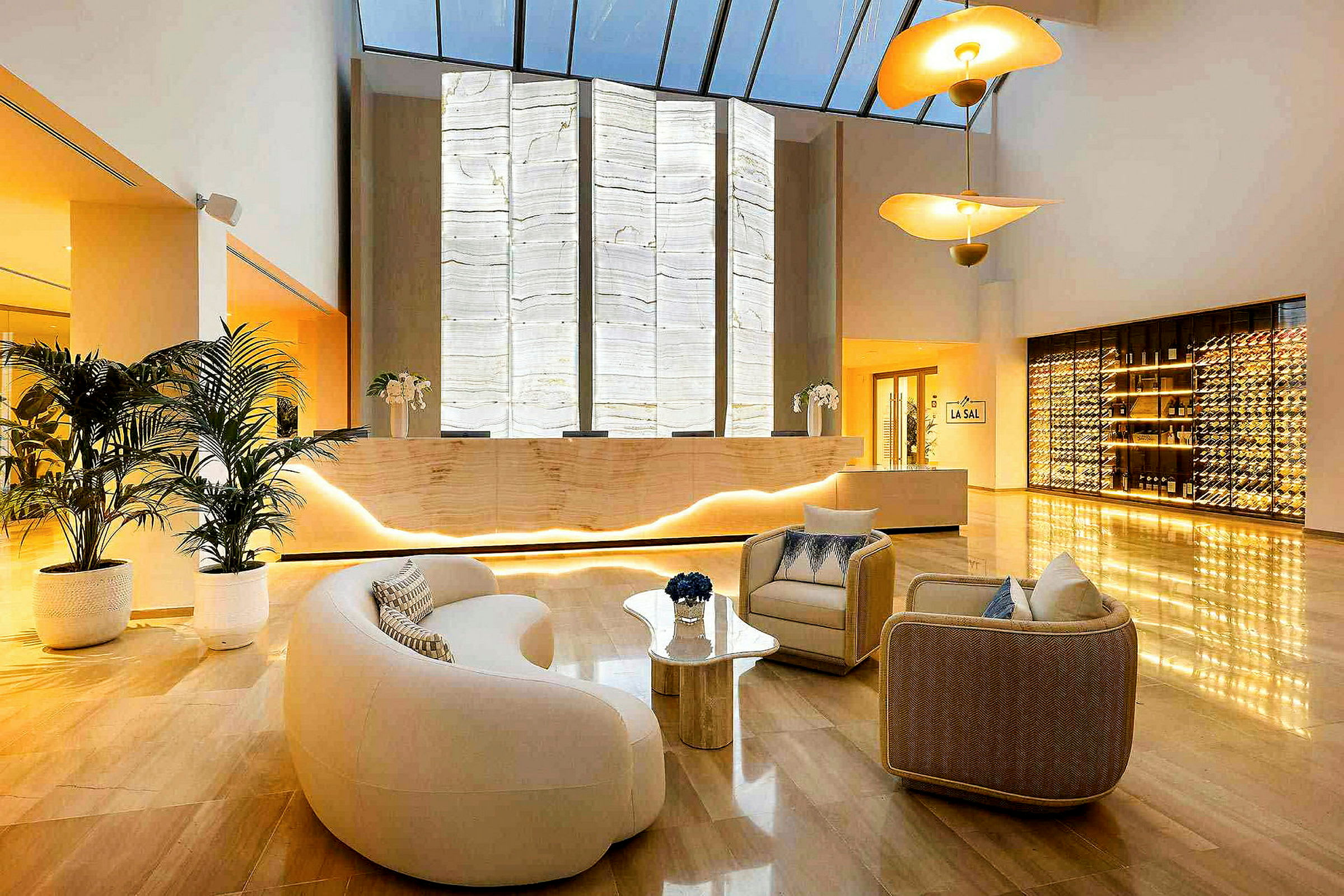 En moderne hotellobby med lænestole, en reception med baggrundsbelyset væg og en vinopbevaringsdisplay. (AI-genereret tekst)