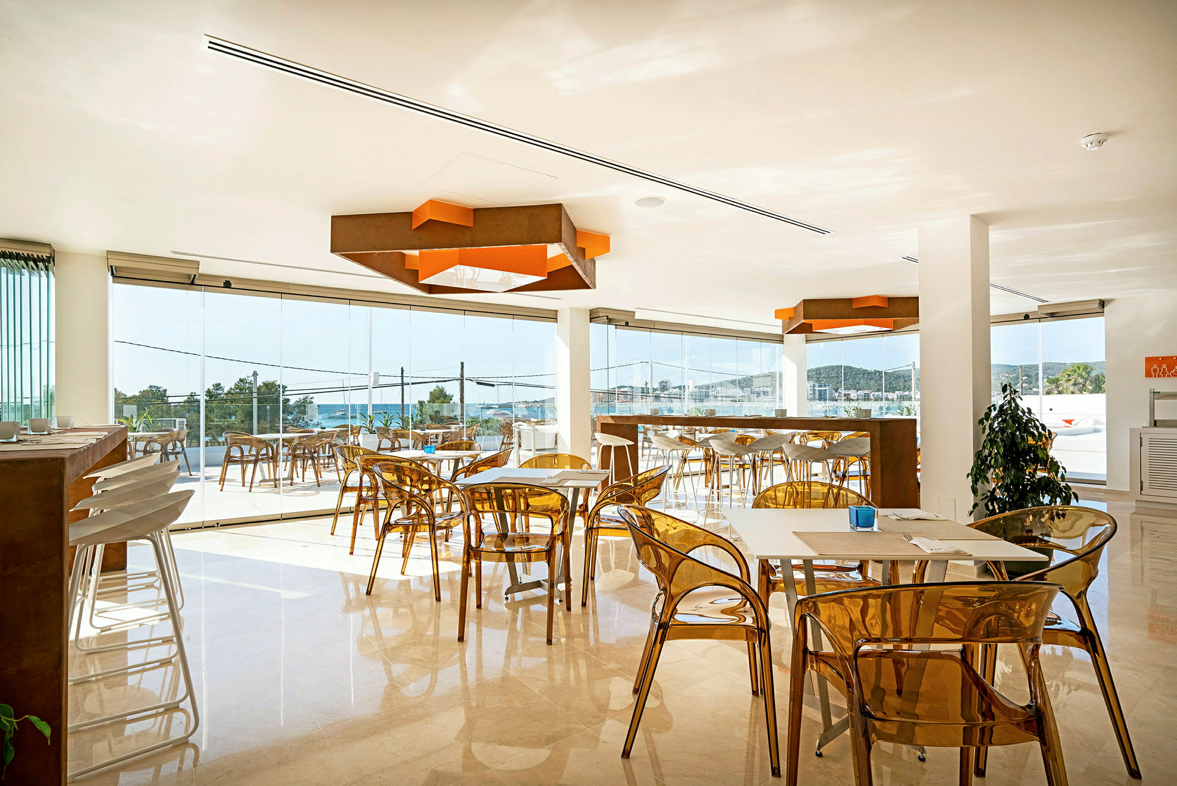 En moderne café med gennemsigtige stole og vinduer med udsigt over havet. (AI-genereret tekst)