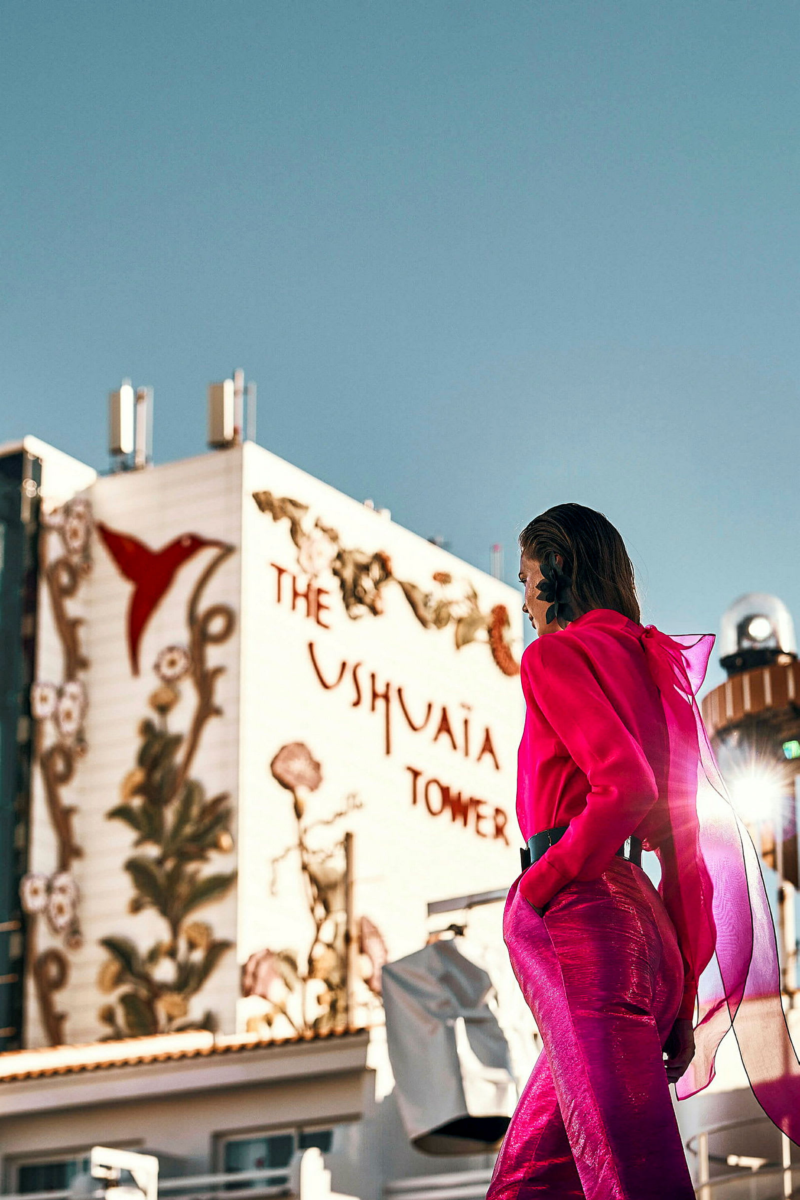 En person i lyserødt tøj foran en bygning med teksten 'Ushuaia Tower' og dekorationer. (AI-genereret tekst)