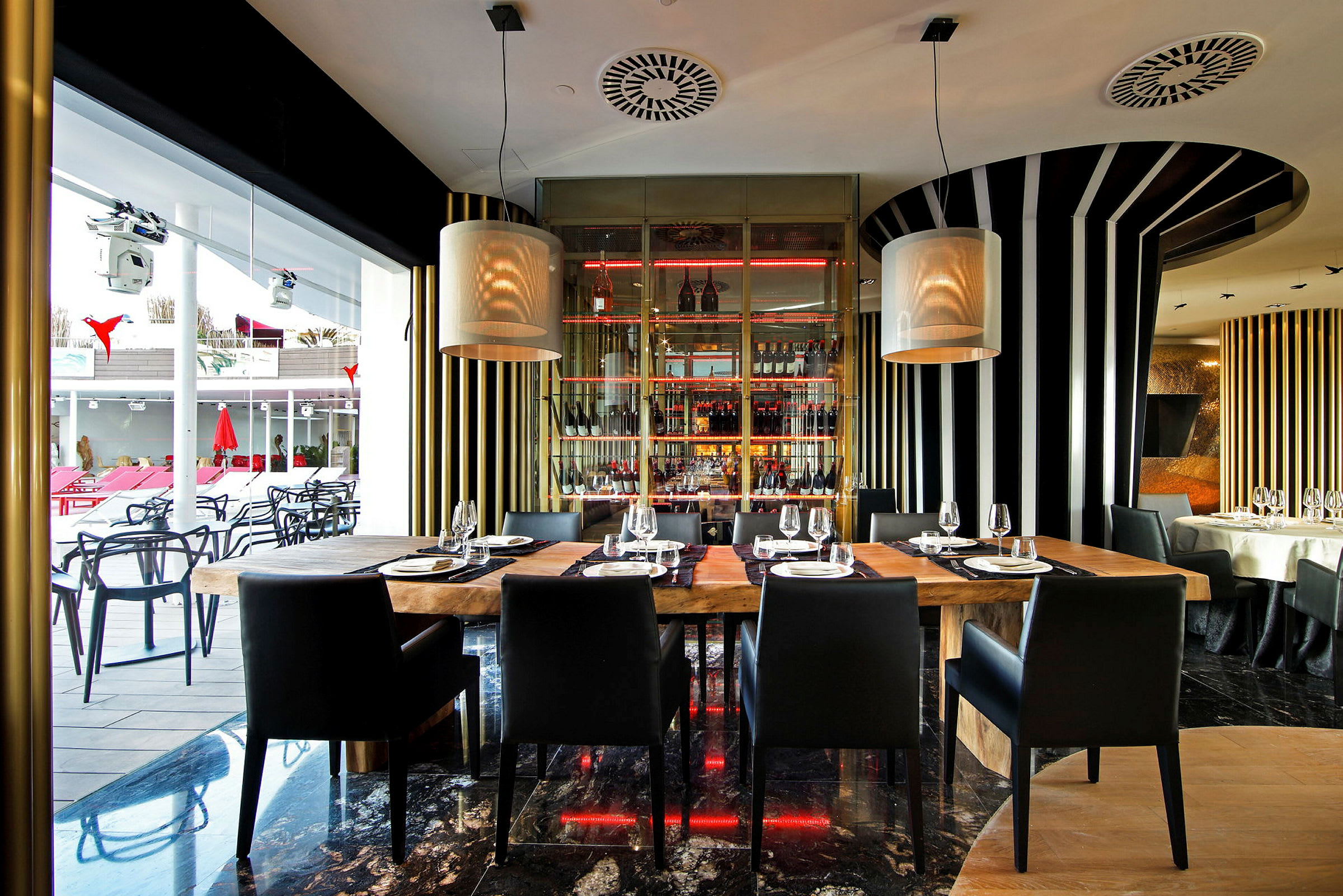 Interiør af en moderne restaurant med træborde og sorte stole, omgivet af stribede vægdekorationer og store vinduer. (AI-genereret tekst)