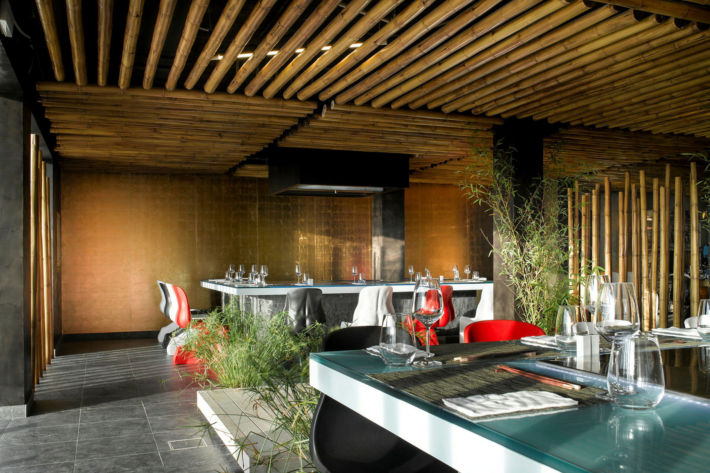Interiør af en moderne restaurant med bambus-inspireret loft, elegante møbler og grønne planter. (AI-genereret tekst)