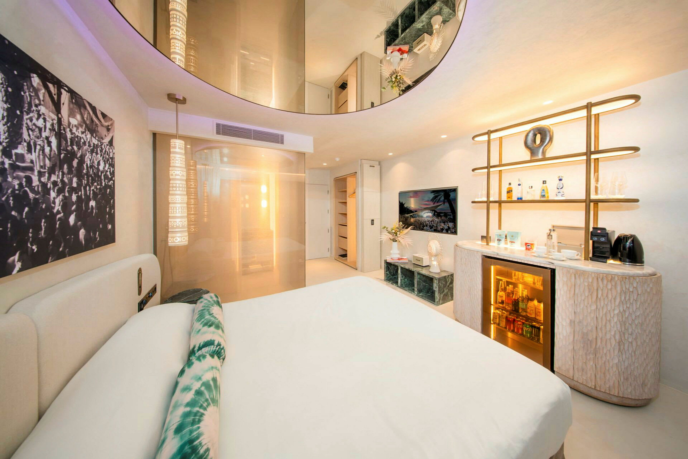 Et moderne hotelværelse med en dobbeltseng, dekorative lys og et minibarområde. (AI-genereret tekst)