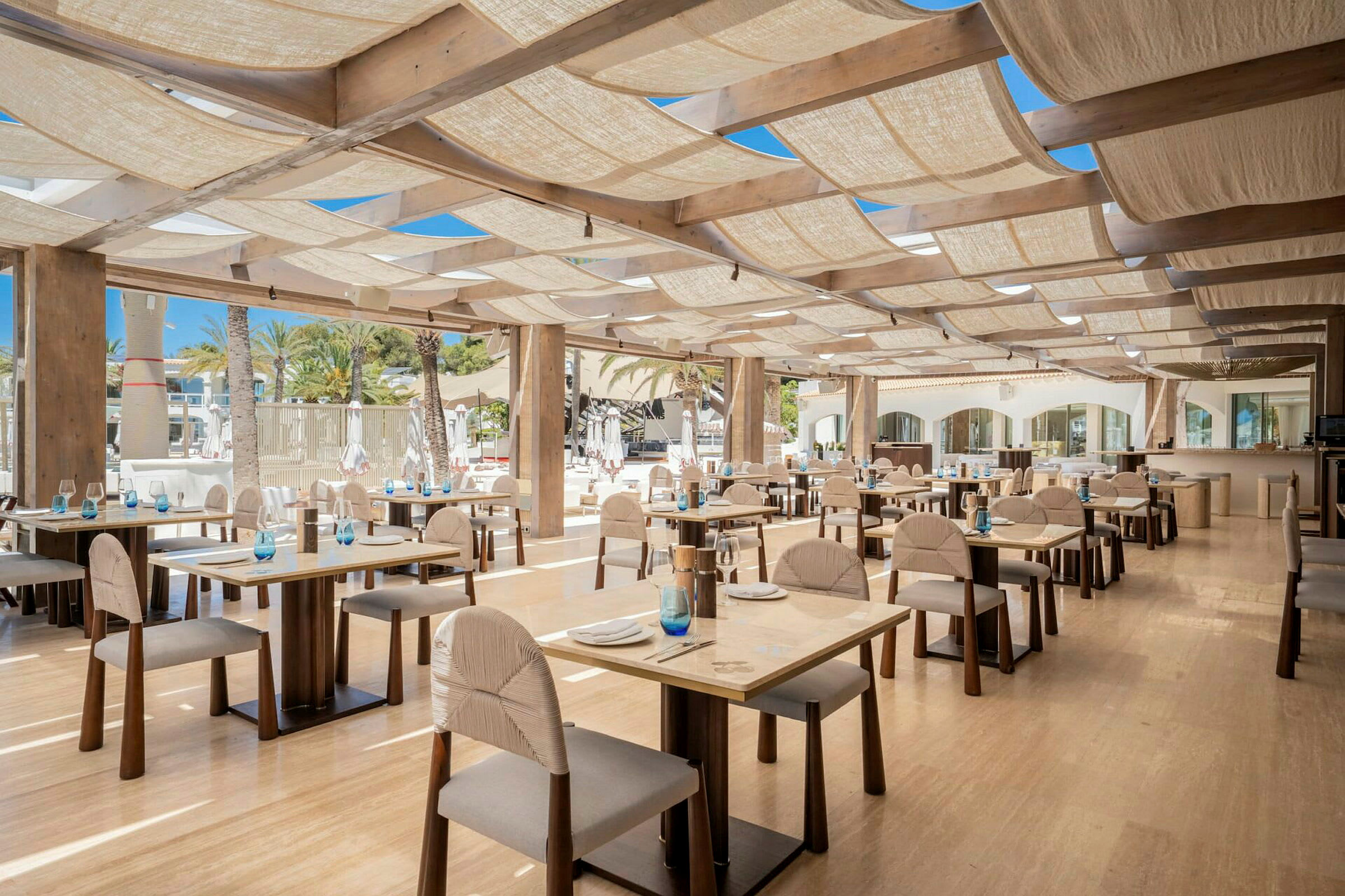 En restaurant med borde og træstole, godt oplyst med naturligt lys. (AI-genereret tekst)