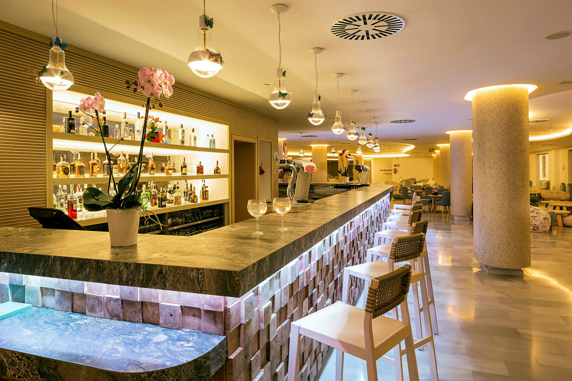 Interiør af en elegant bar med bardisk, stole og flasker arrangeret på hylder. (AI-genereret tekst)