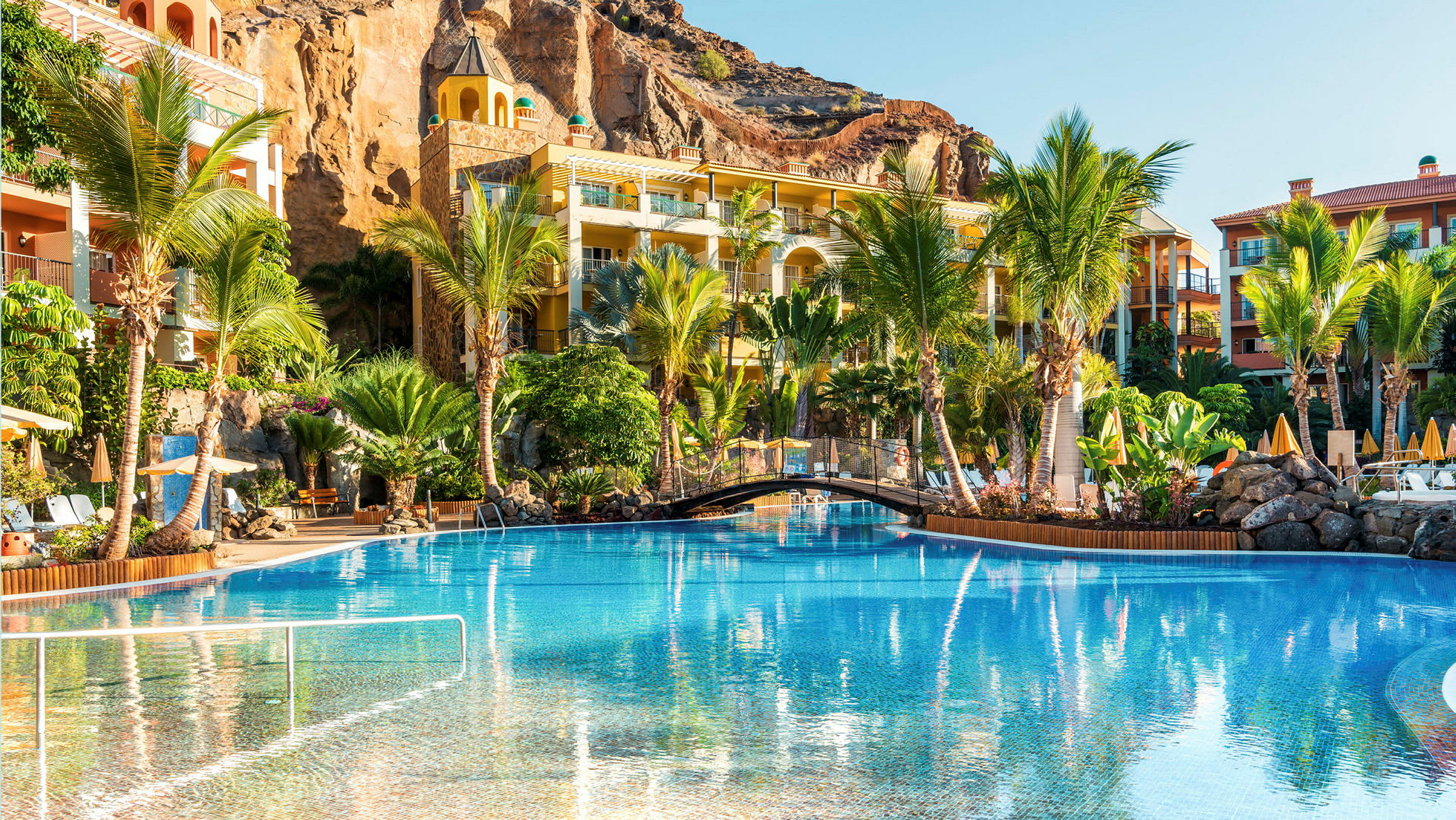 Hotelområde med pool, palmer og bygninger. (AI-genereret tekst)