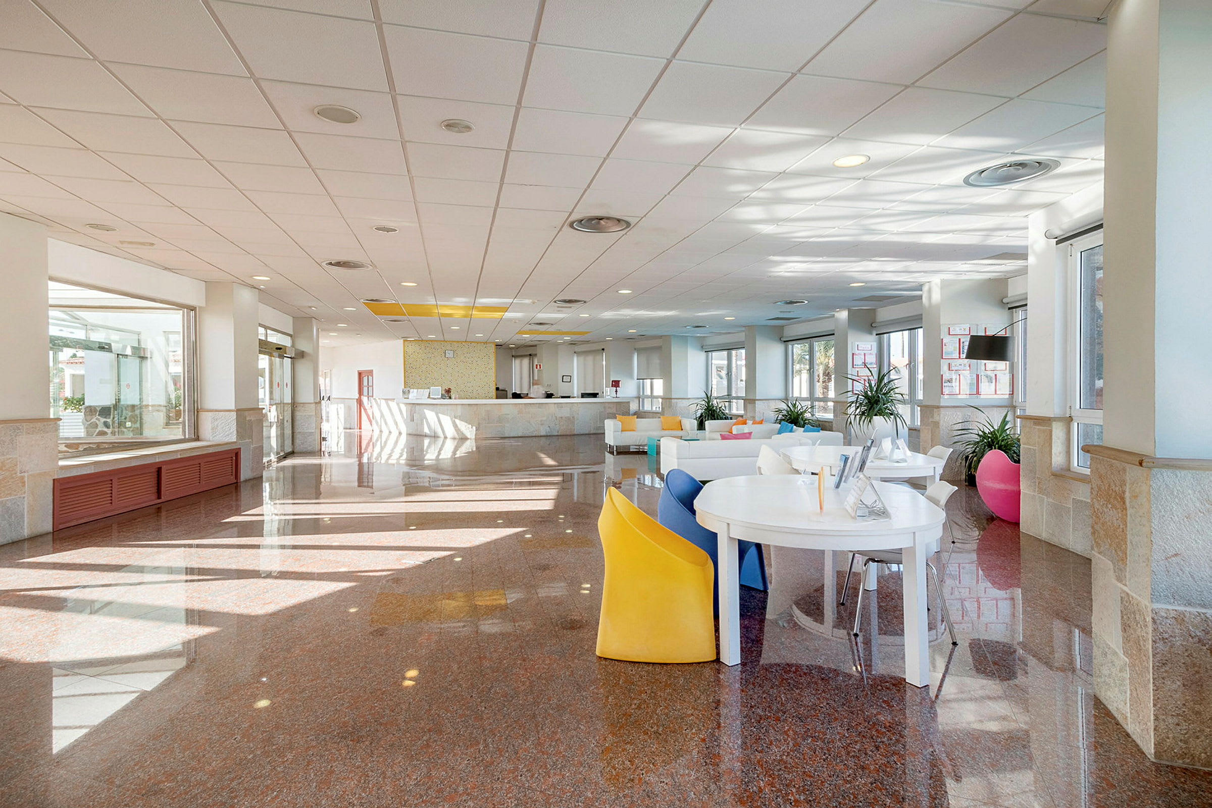 Billede af en hotellobby med en receptionsskranke og siddeområder. (AI-genereret tekst)