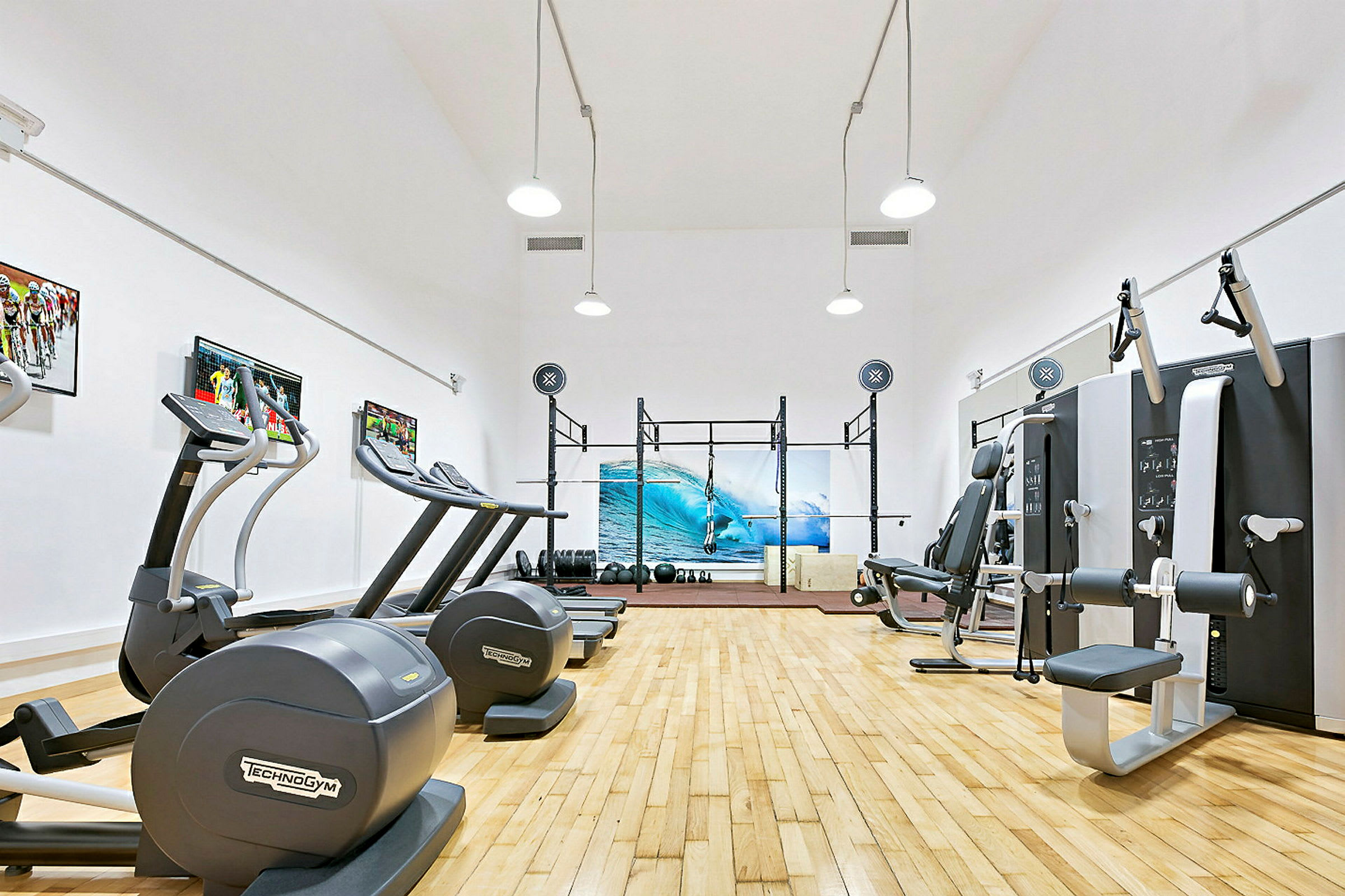 Et fitnesscenter med træningsudstyr og et billede af en surfebølge på væggen. (AI-genereret tekst)