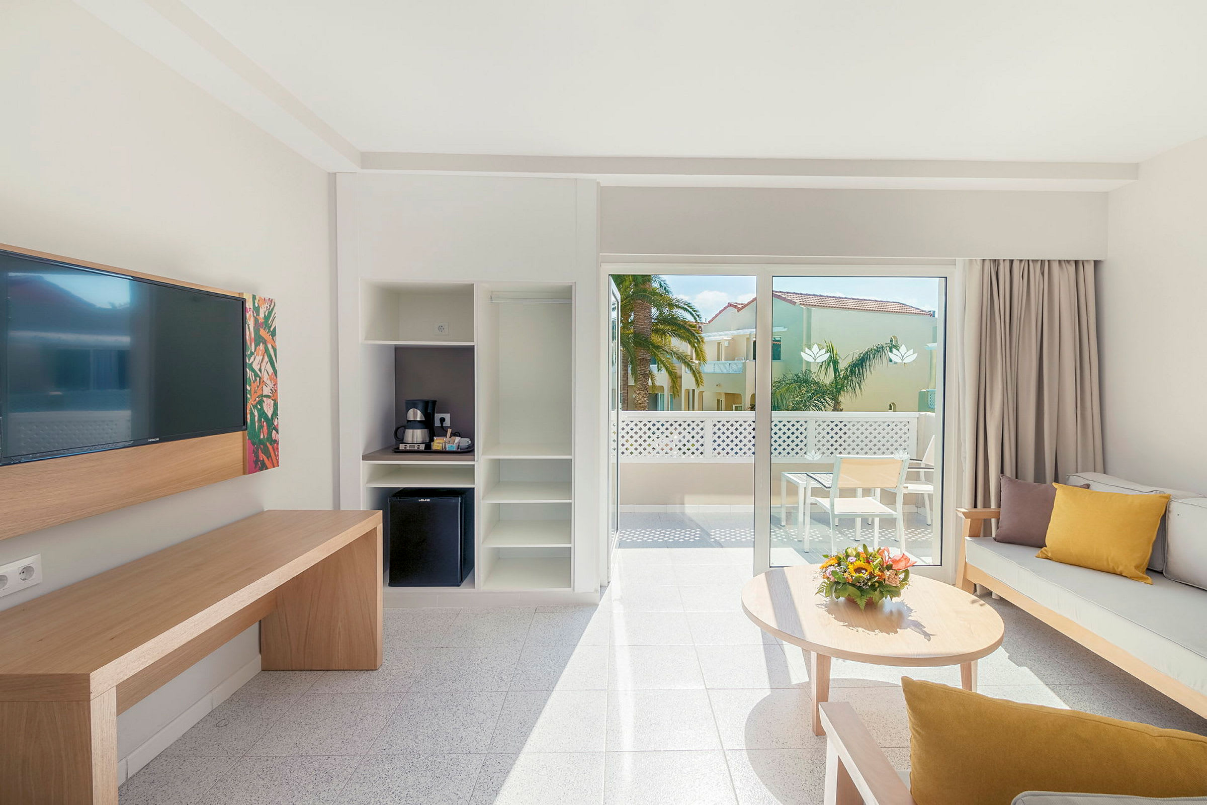 Et moderne hotelværelse med siddeområde og adgang til en solrig balkon. (AI-genereret tekst)