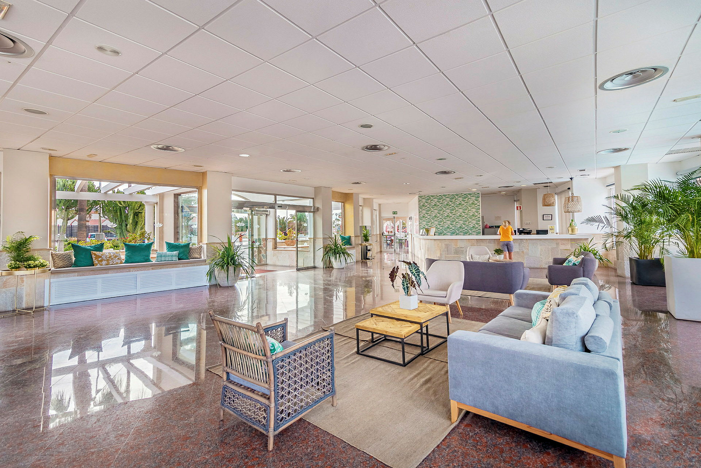 Hotellets lobby med siddeområder, reception og dekorative planter. (AI-genereret tekst)