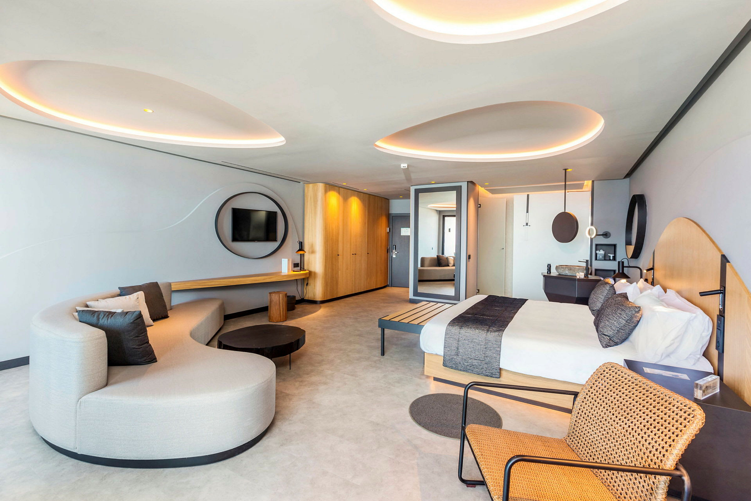 Et moderne hotelværelse med en seng, en sofa og en stol med flettet design. (AI-genereret tekst)