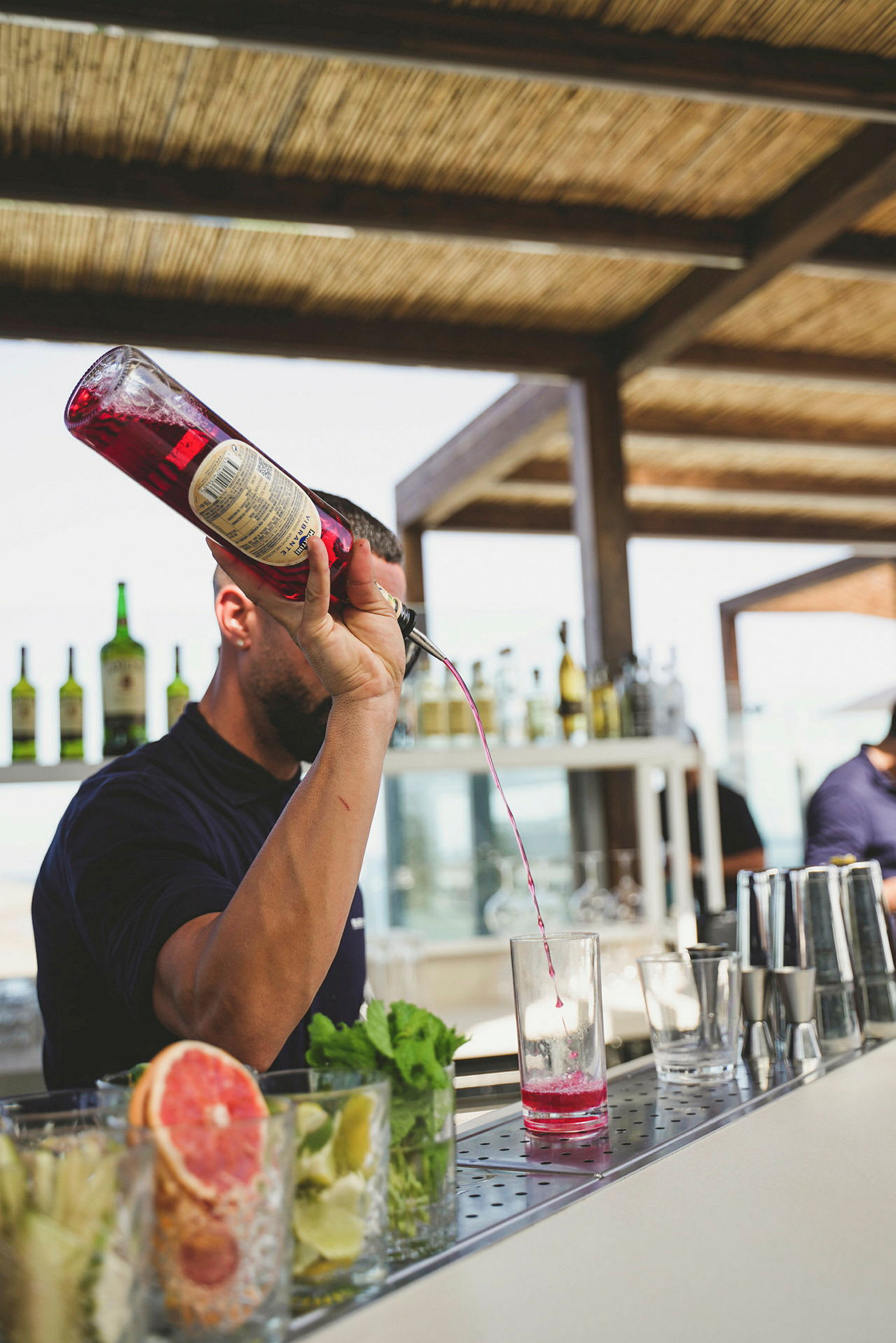 Billede af en bartender, der hælder lyserød væske i et glas. (AI-genereret tekst)